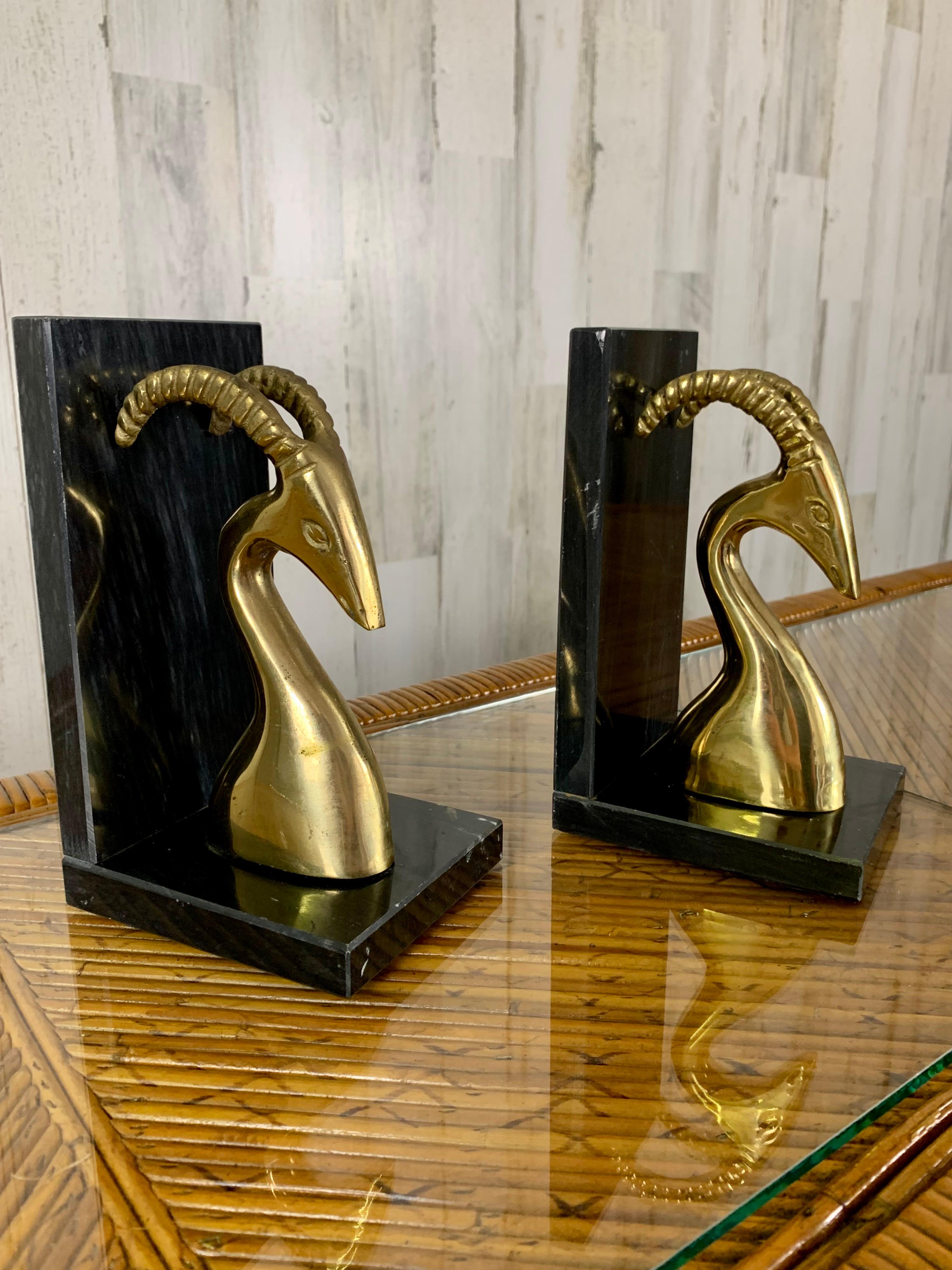 Pair of brass gazelle sculptures mounted on black marble stands.