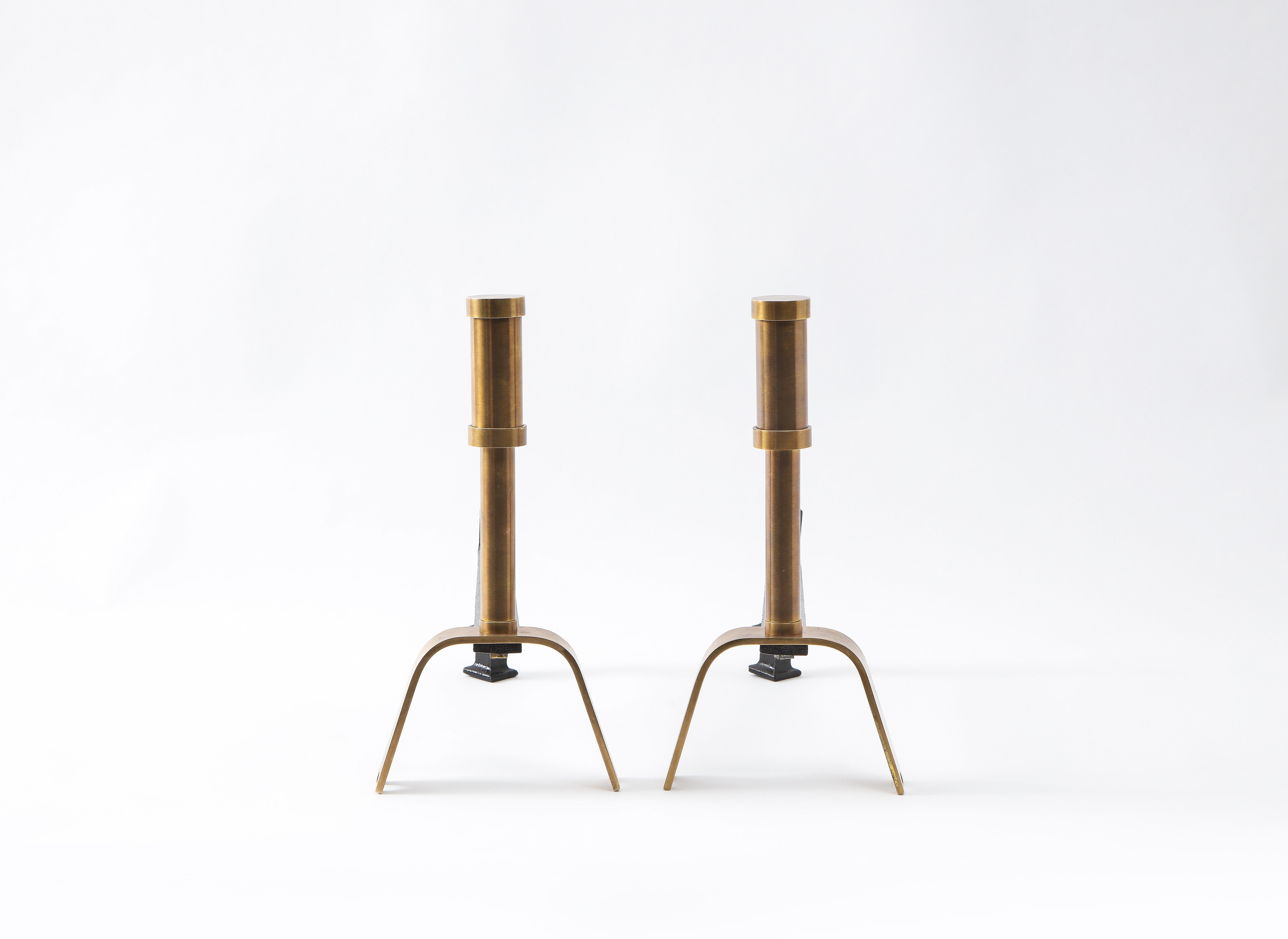 Elegant pair of modernist andirons made of stacked brass tubes on a U-shaped brass foot.