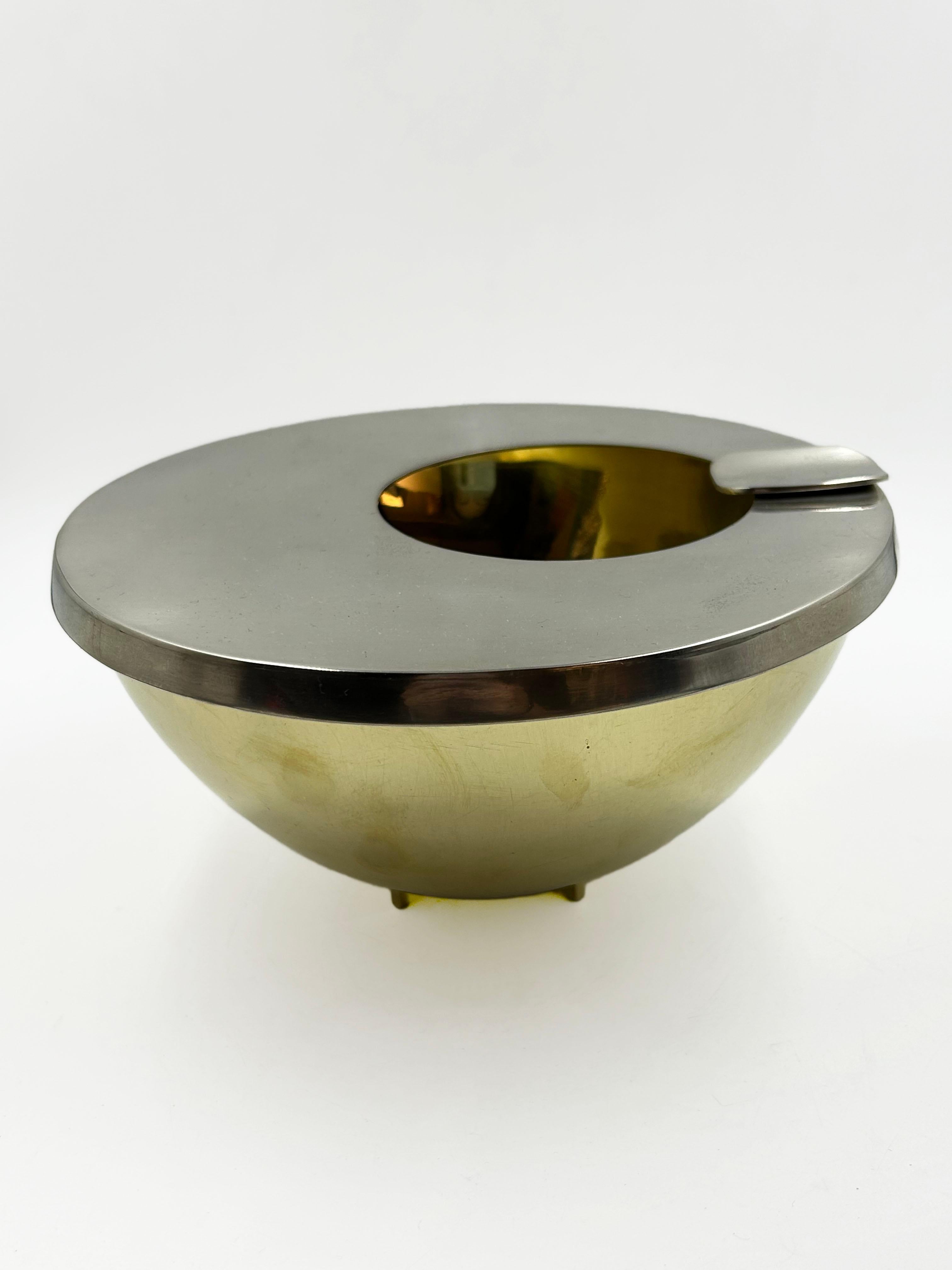 Der klare, halbkugelförmige Korpus auf kleinen Füßen und die flache, runde Platte mit integrierter Zigarettenablage betonen die reine Form und den praktischen Nutzen, die für das Bauhaus-Design charakteristisch sind.

Der Kontrast zwischen der