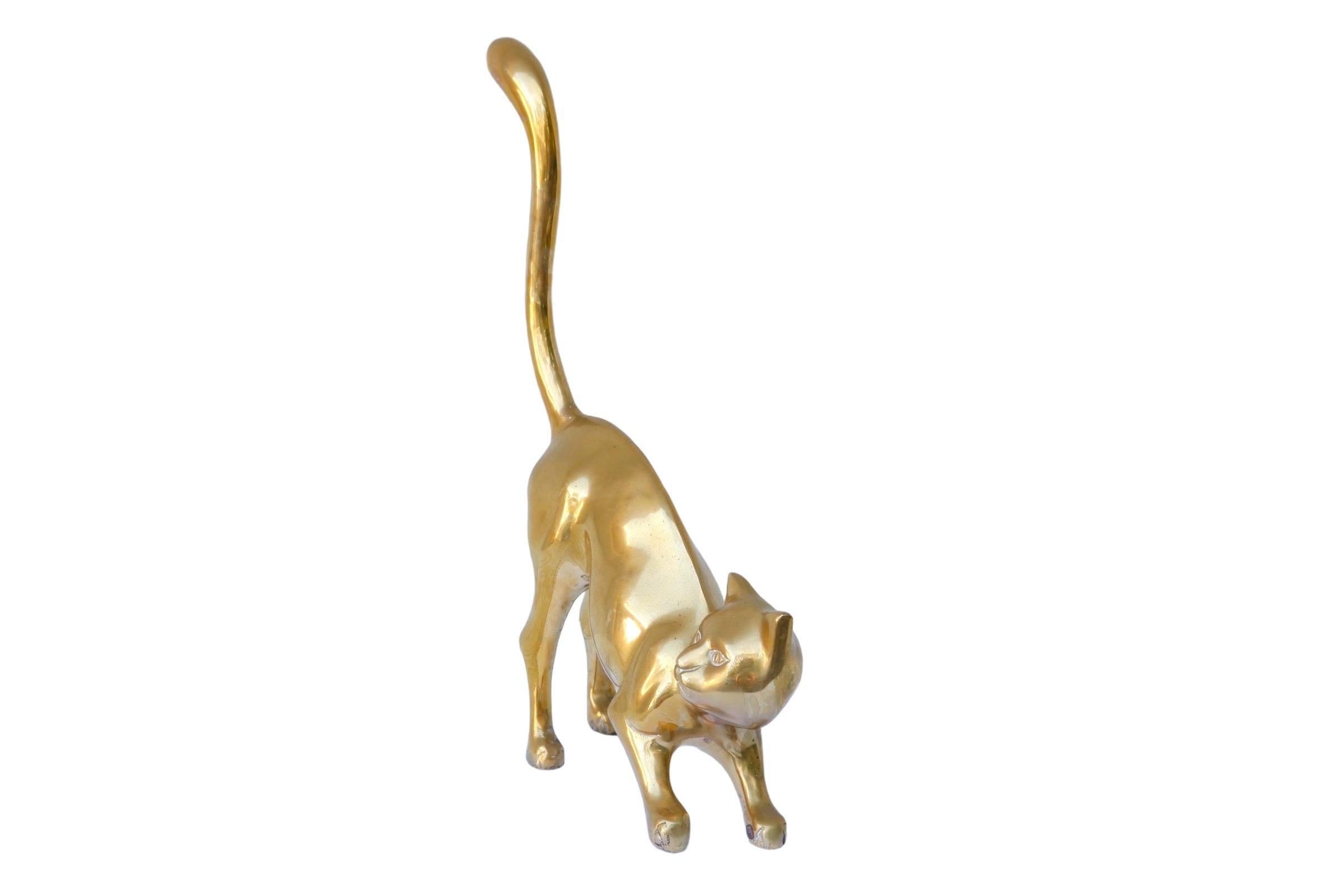 A modernist brass cat in a curious pose, with an unimpressed expression. Cast with fluid lines curved through the tail and arched back. Finished with simple lines detailing the eyes, nose, mouth and toes.