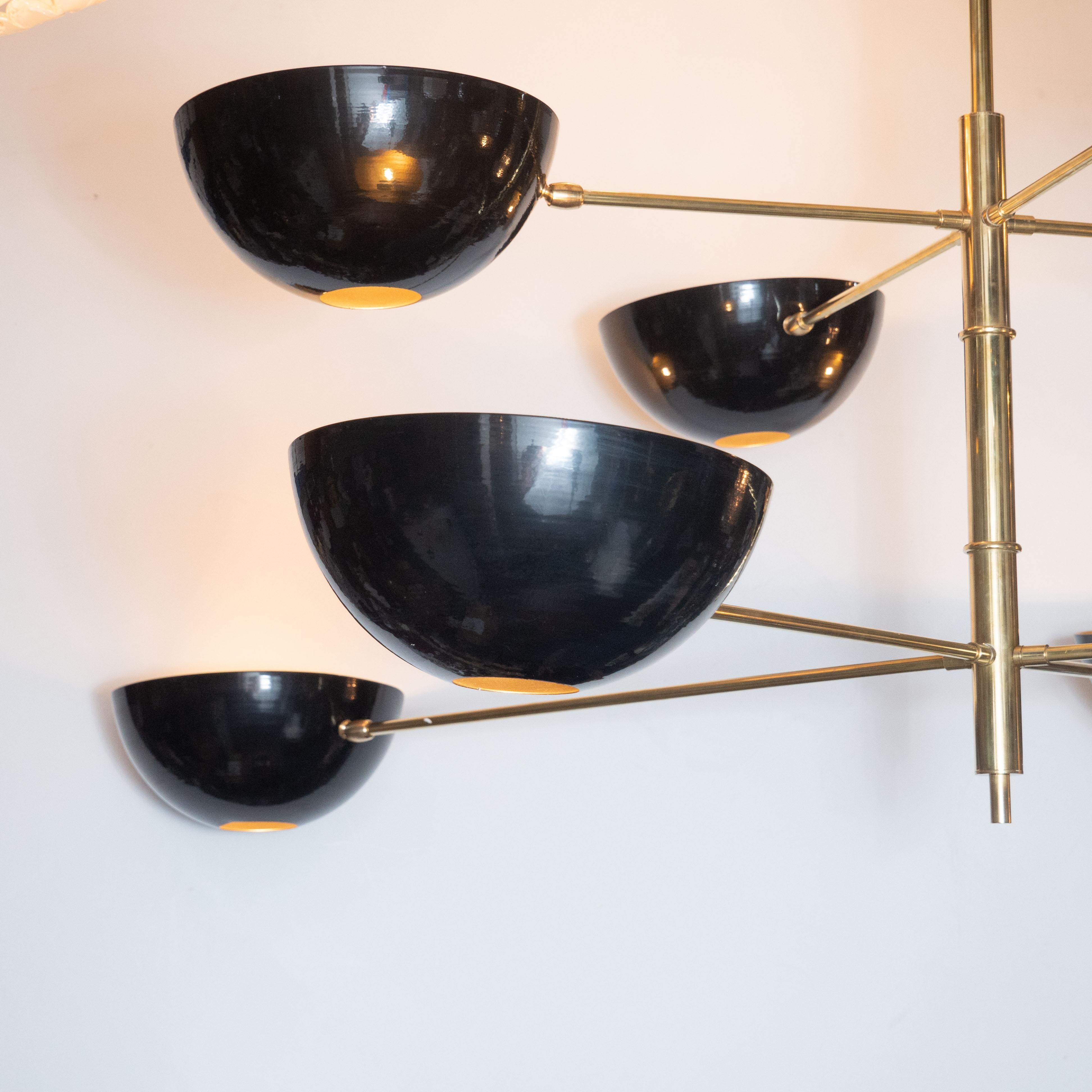 This stunning modernist eight-arm Stilnovo style chandelier was designed and created in Italy by High Style Deco. It features two sets of four brass arms that cross the cylindrical body in an x-form. Each of the arms culminate in a convex domed
