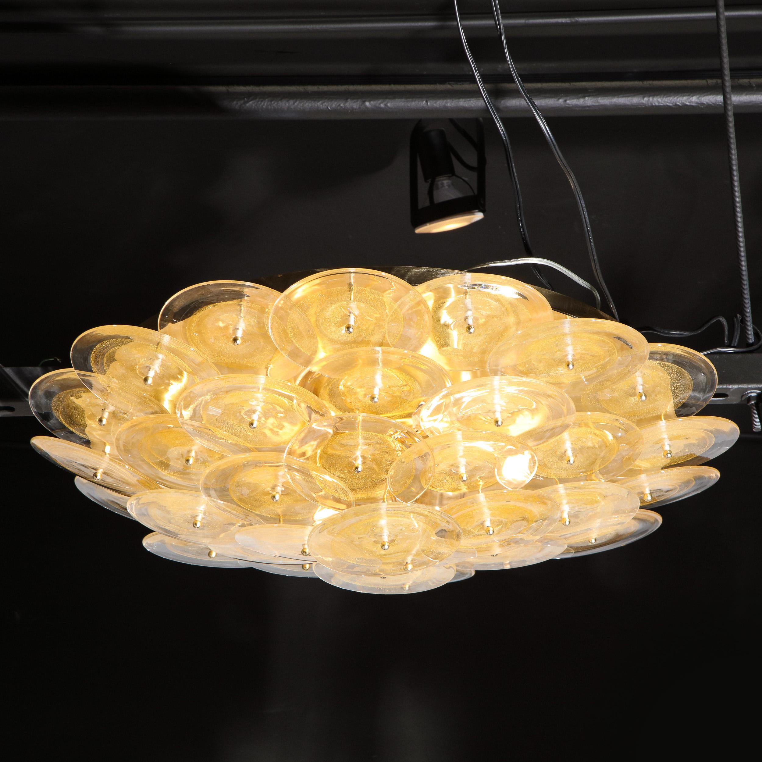 This handblown Murano chandelier is composed of an abundance of overlapping translucent Murano discs with 24kt yellow gold flecks attached to a polished brass base. The disks are connected to the base by brass rods, whose ends gently protrude