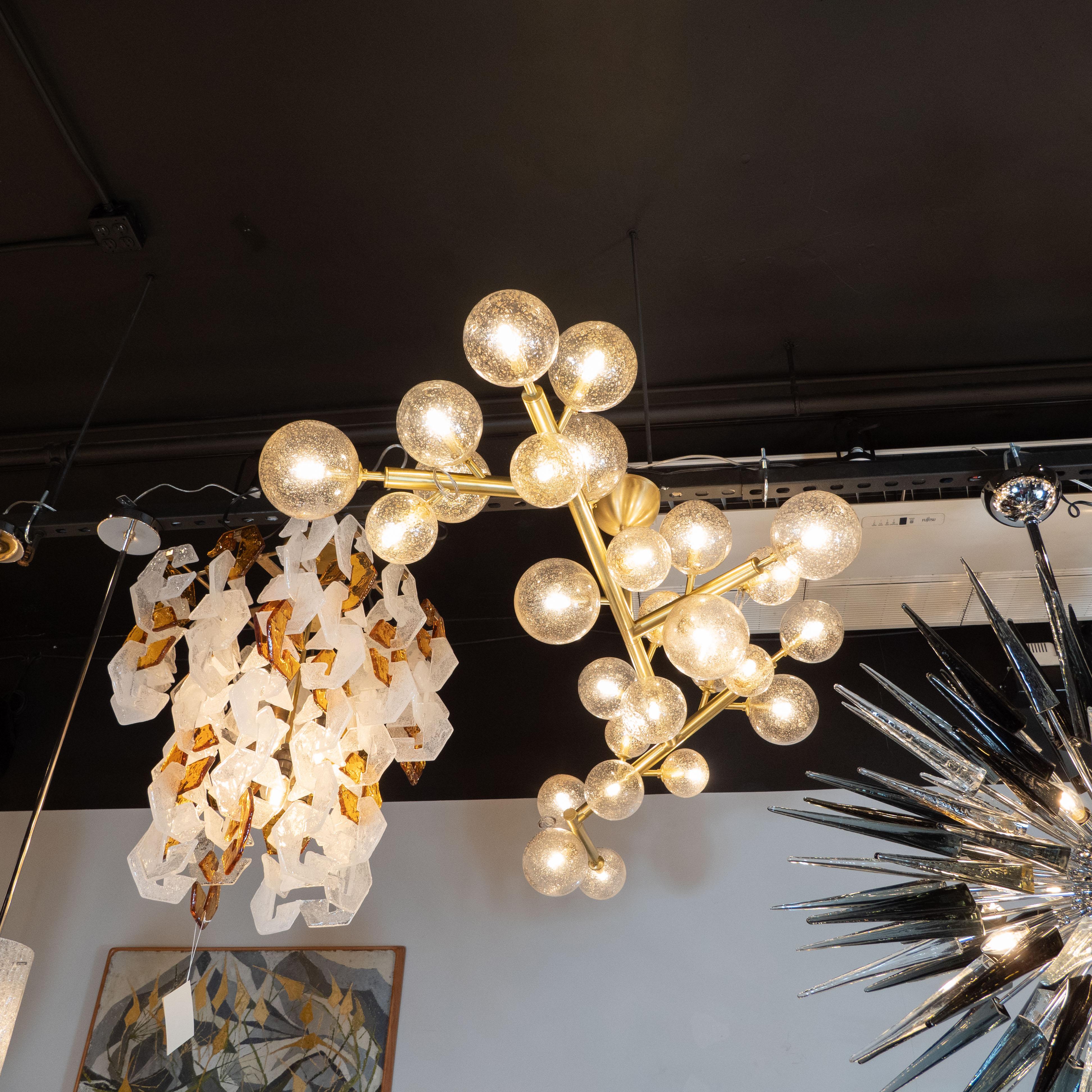 This stunning and graphic modernist brass snowflake chandelier was realized in Murano, Italy- the island off the coast of Venice renowned for centuries for its superlative glass production. It features an organic branch-like form in brass capped at