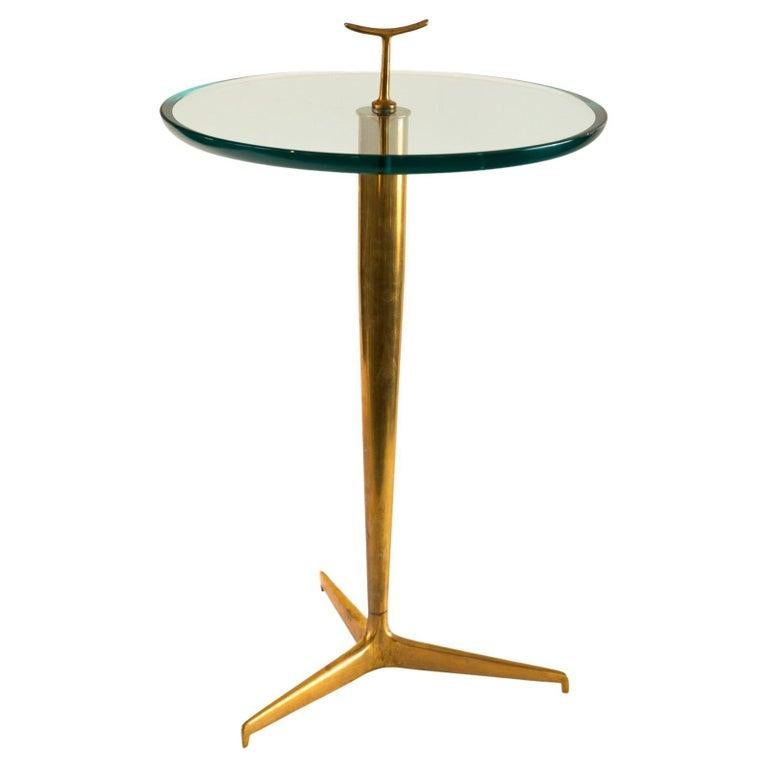 Modernist Drinks Table with a thick beveled and polished lens cut glass top floating on a graceful tripod base frame with a small brass handle detail. Frame is quite heavy for its size as the brass is cast with a patinated finish.

Origin: