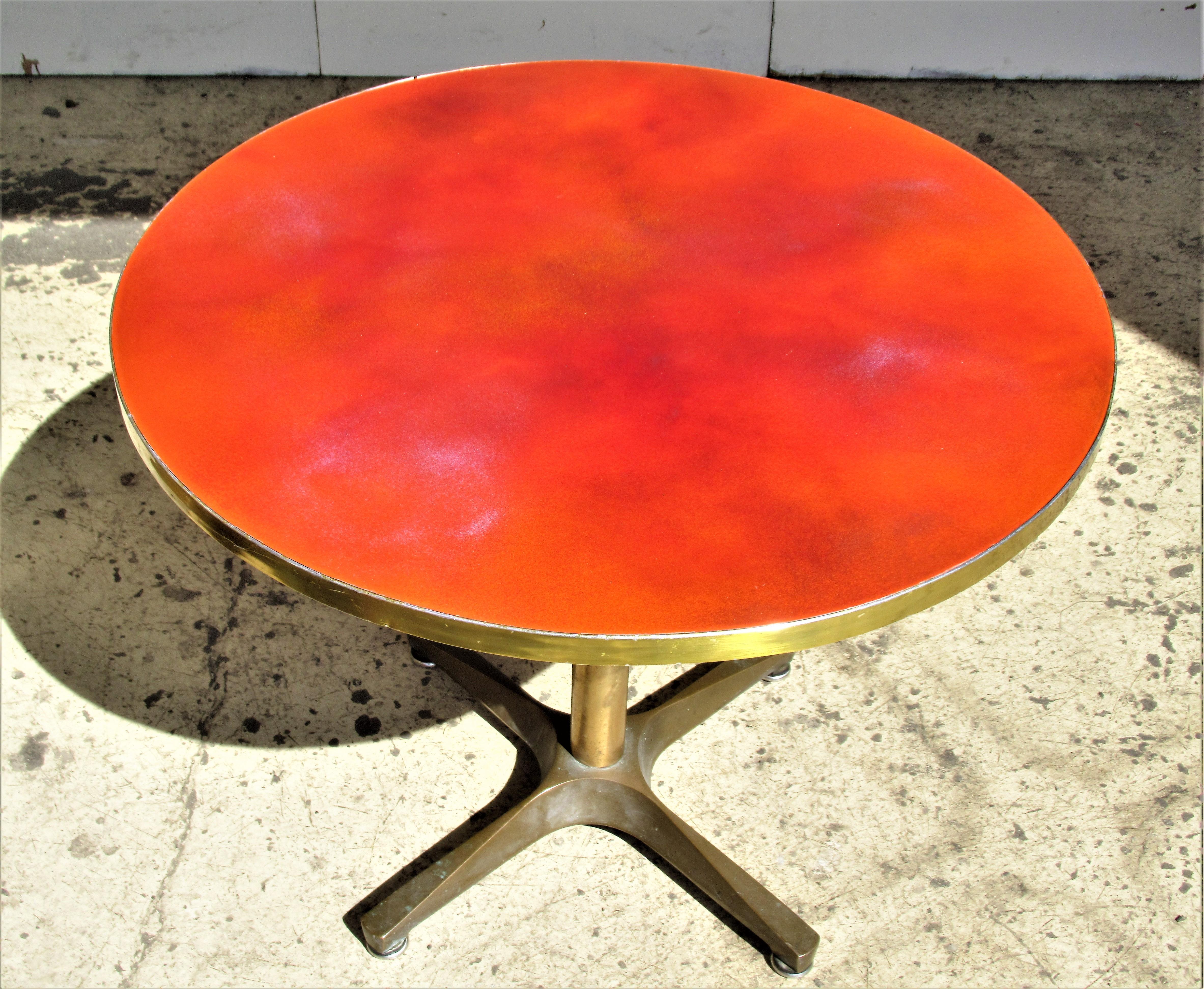 Modernist bronze X base swivel table with brilliant variegated orange and violet enameled metal brass trimmed top. Heavyweight industrial quality and great sculptural form. The height will raise up to 26 inches and fit tight in this position but