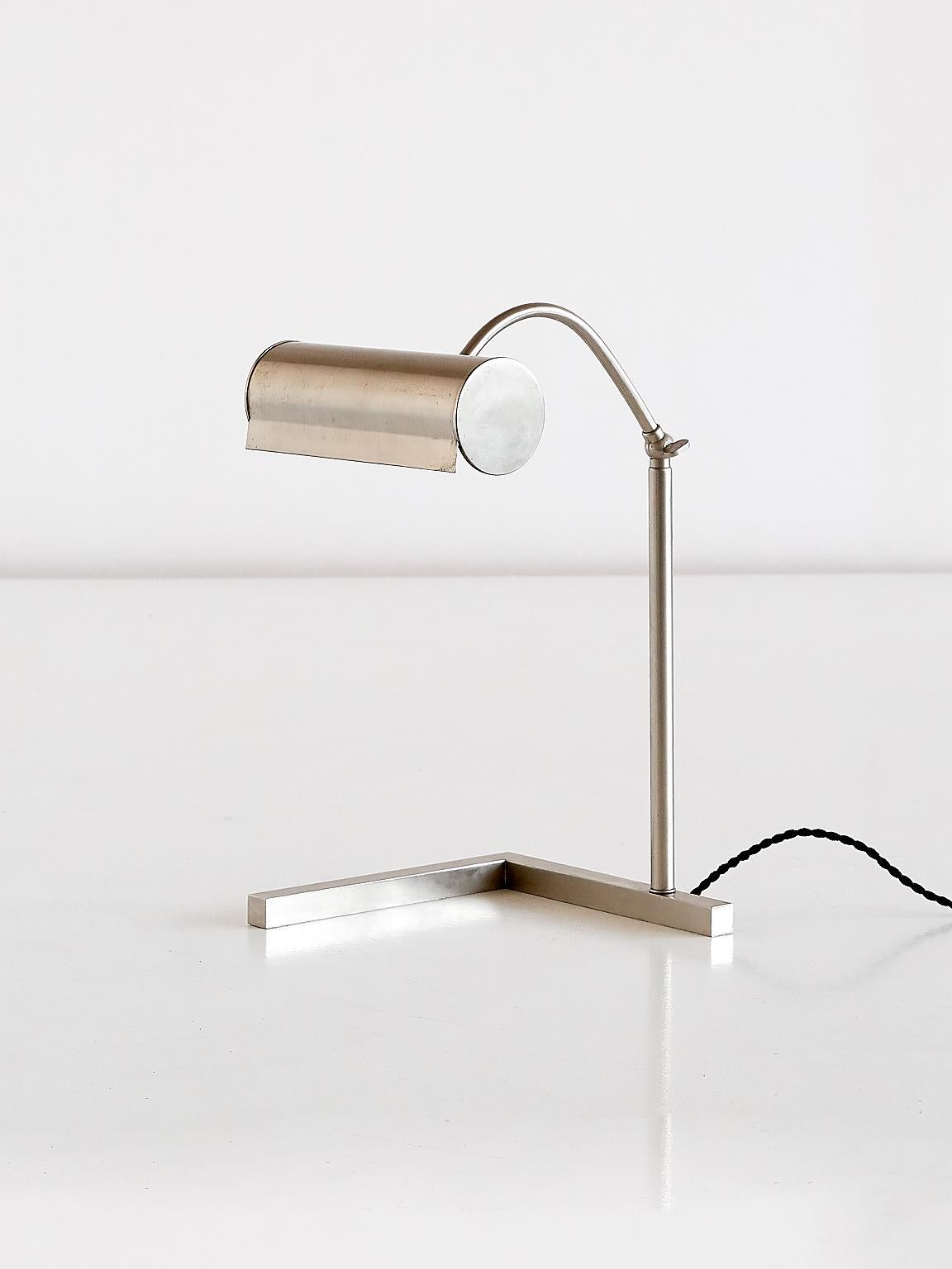 This striking desk or table lamp in brushed steel was manufactured in The Netherlands in the 1930s. The lamp consists of an L shaped base, with a cylindrical adjustable shade. Reminiscent in style and execution of the work by Dutch contemporaries