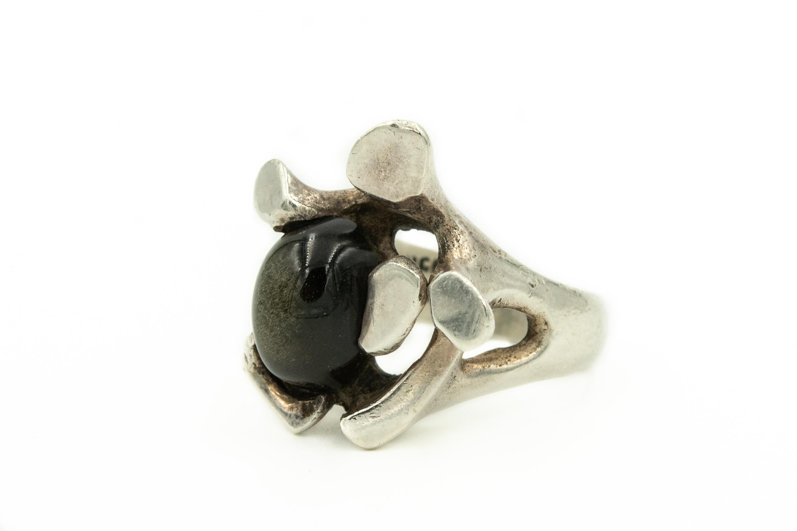 Modernist Mexican sterling silver ring by Mateo featuring a cabochon black sapphire mounted in a silver design.  The large chunky stamen-like shapes surround the gem, with several acting as prongs. Three additional smaller prongs hold the 9.5mm x