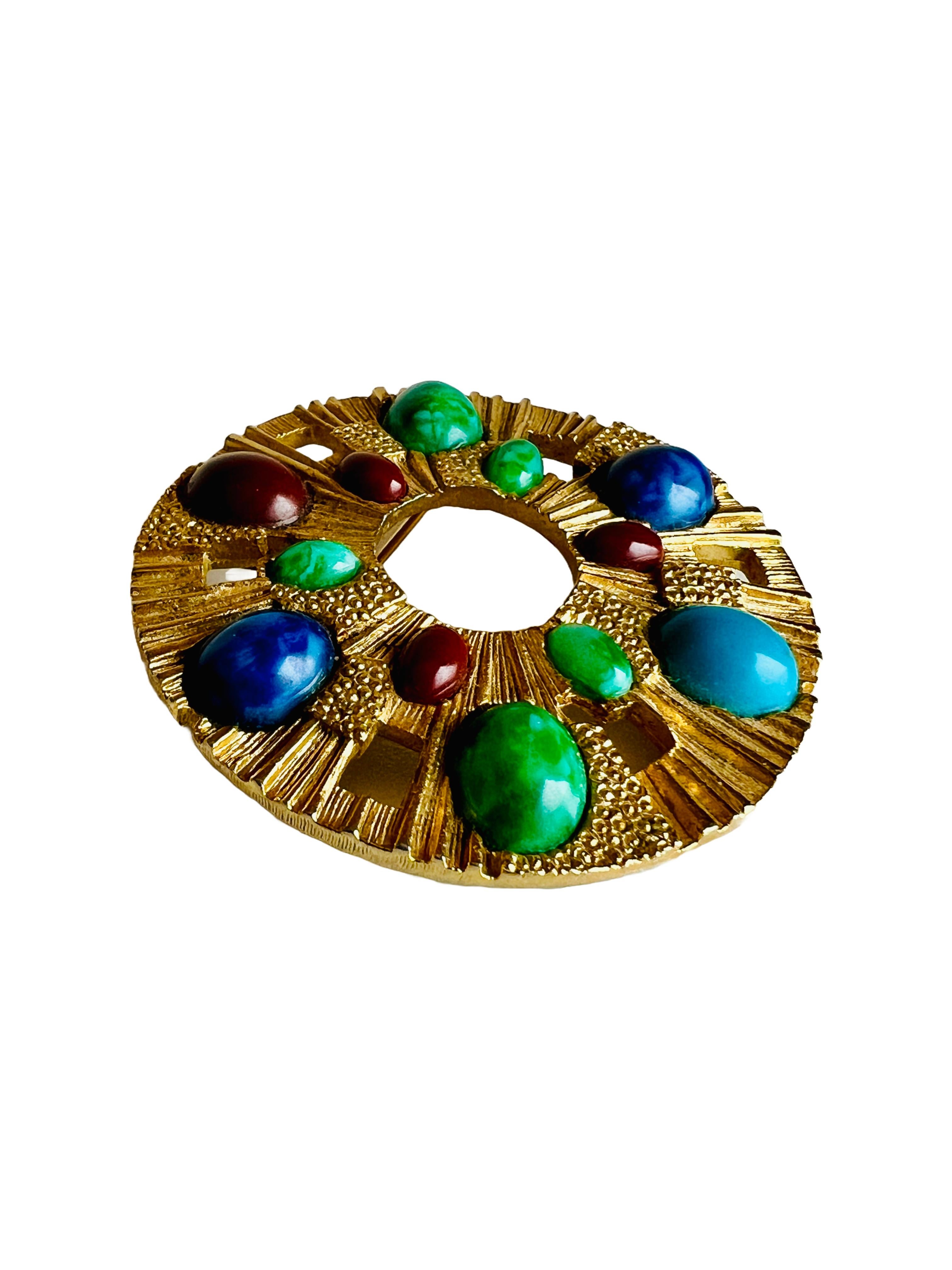 This vintage gold medallion brooch/pendant captures the essence of bold statement jewelry, blending influences from ancient cultures into a sophisticated, haute couture-inspired design. The circular design features an open center surrounded by