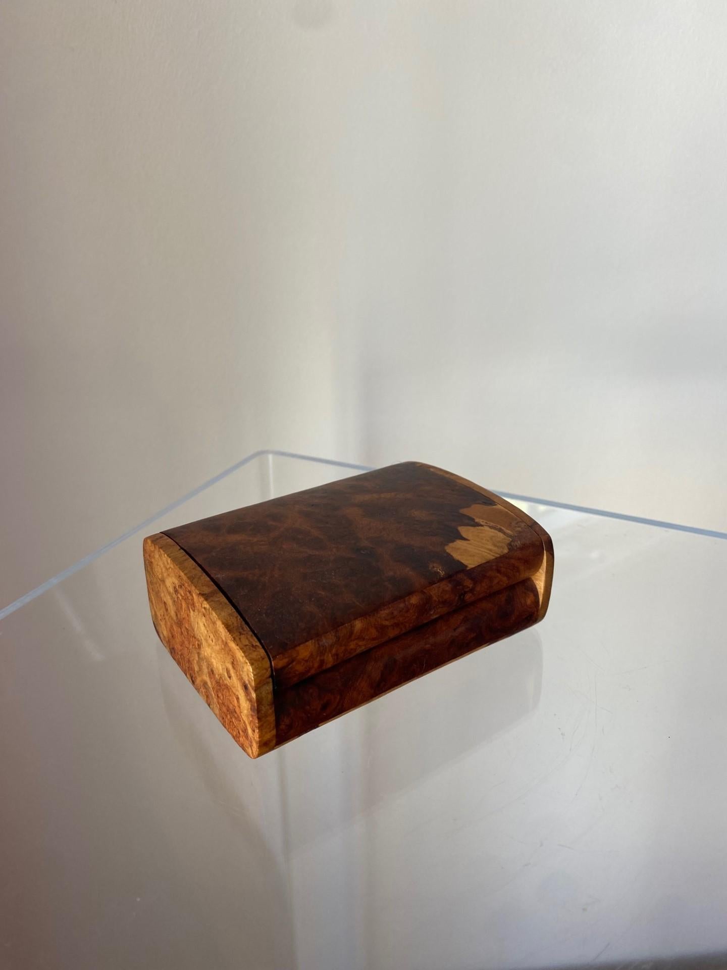 An unusual and streamlined burl wood trinket box, circa 1990s. The box has a movable lid and is in great vintage condition.  Incredibly beautiful piece that exudes organic modern style with a minimal footprint.

Mid-Century, Hollywood Regency, Art