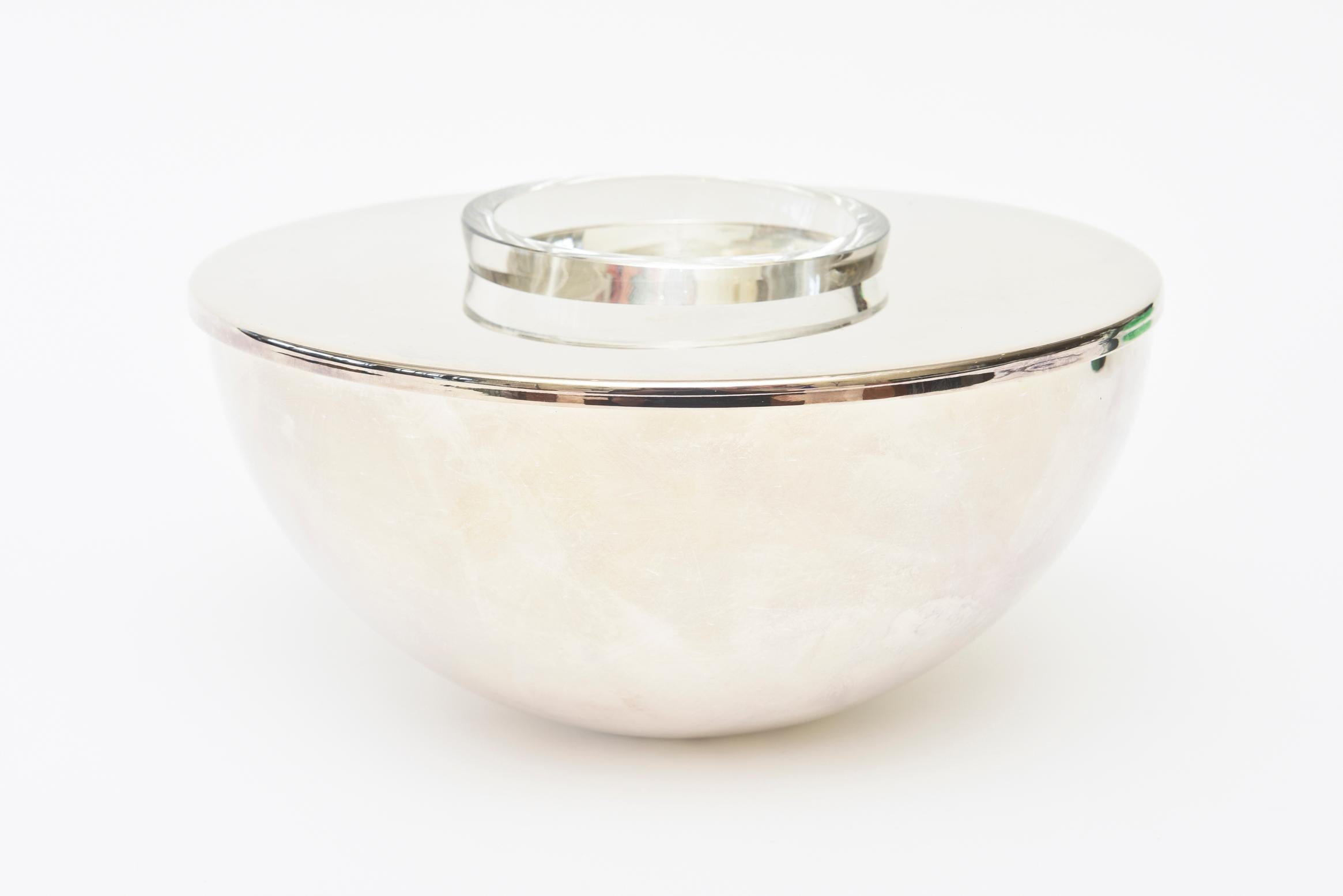 This chic and modernist 1980s silver plate caviar serving bowl and or barware is hallmarked Calvin Klein- Swid Powell. It comes with a mother of pearl serving spoon as an added bonus serving piece. The bowl was manufactured in Hong Kong and the
