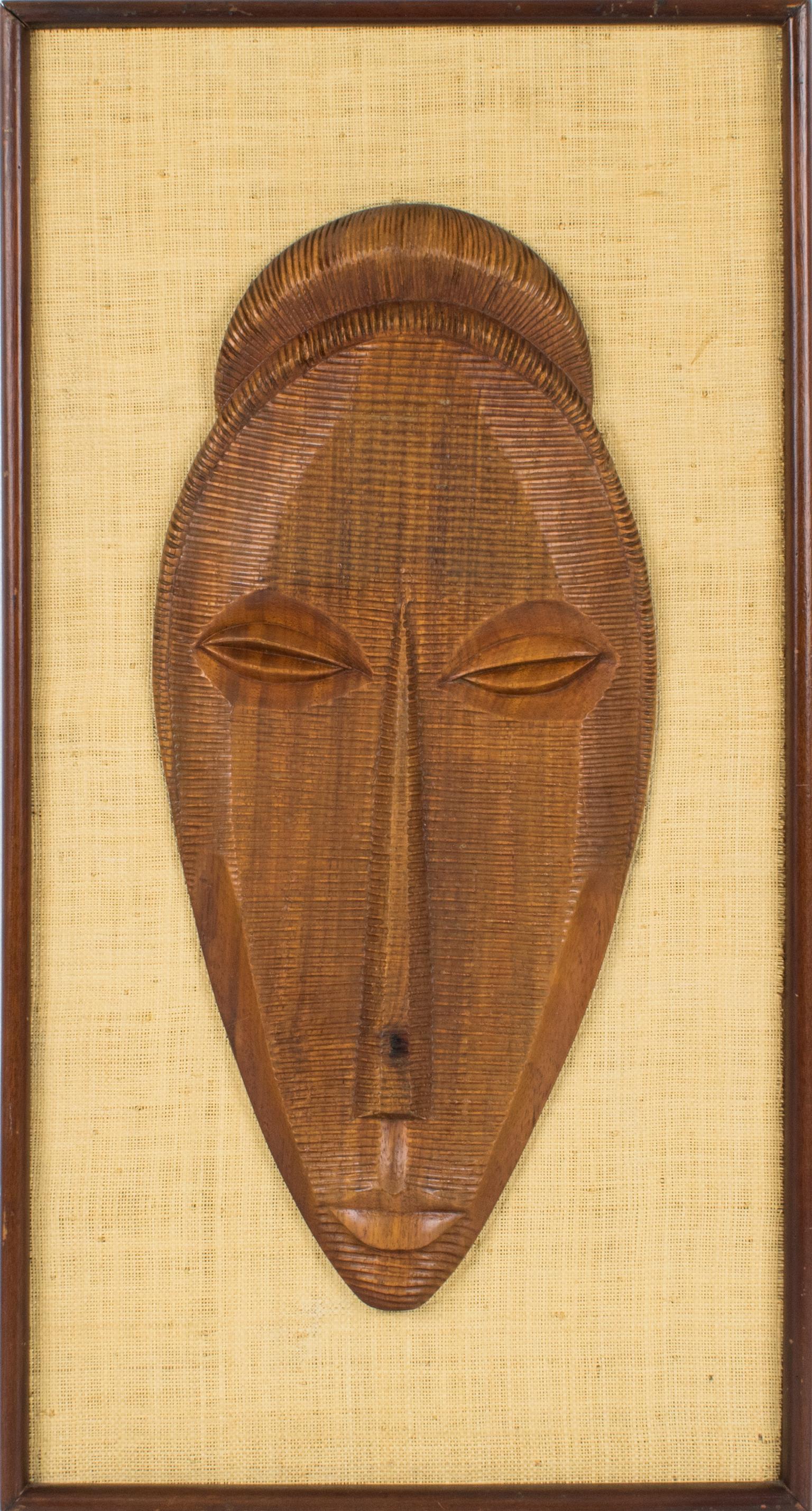 Par de paneles escultóricos de madera de mediados de siglo, magníficamente elaborados a mano. Las obras presentan rostros femeninos y masculinos dimensionales o máscaras en relieve de madera con formas estilizadas y talla geométrica profunda. La