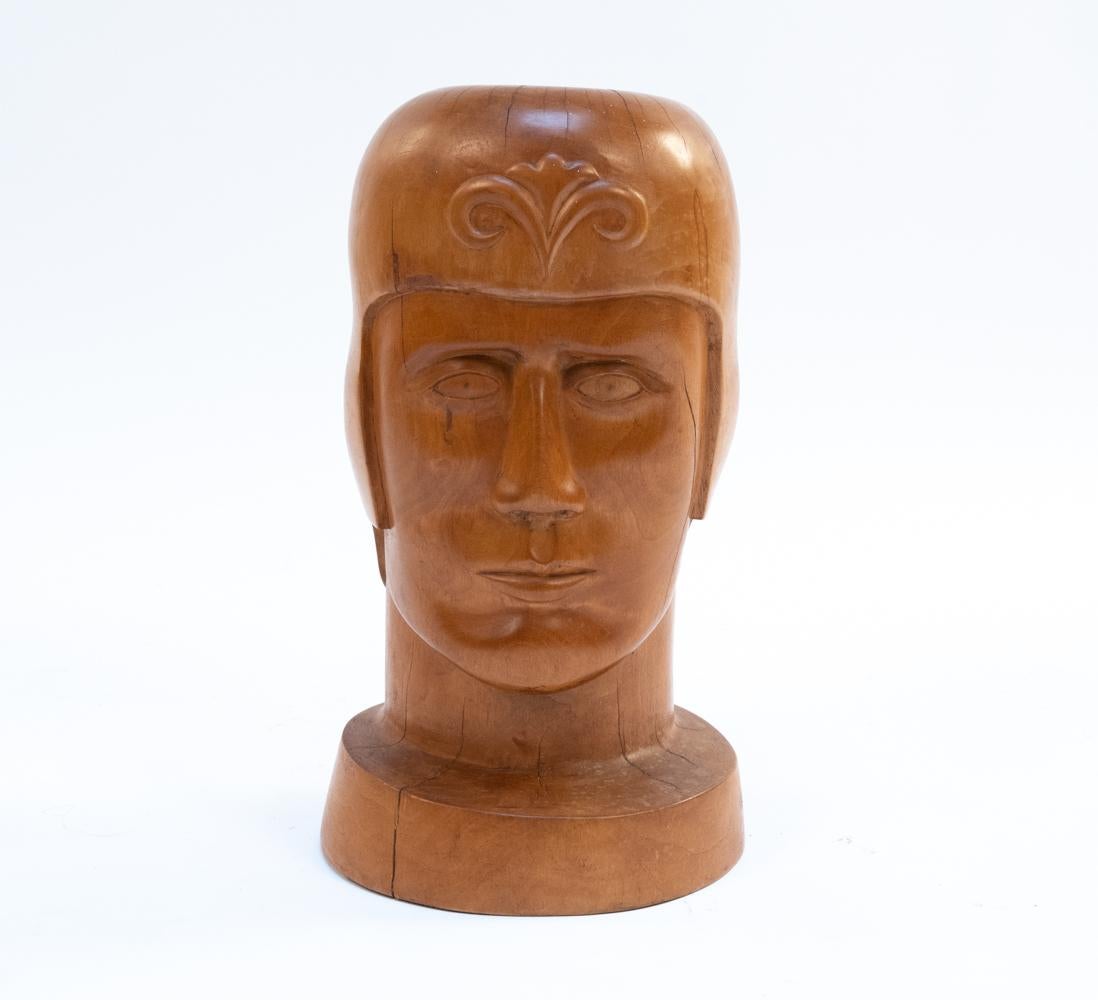 Apparently unsigned. Reminiscent of the style of 1940s WPA artists, this resolute head is carved from beautiful curly blonde wood and features a helmet emblazoned with a floral emblem. It's the perfect size for a bookshelf or tabletop decoration!