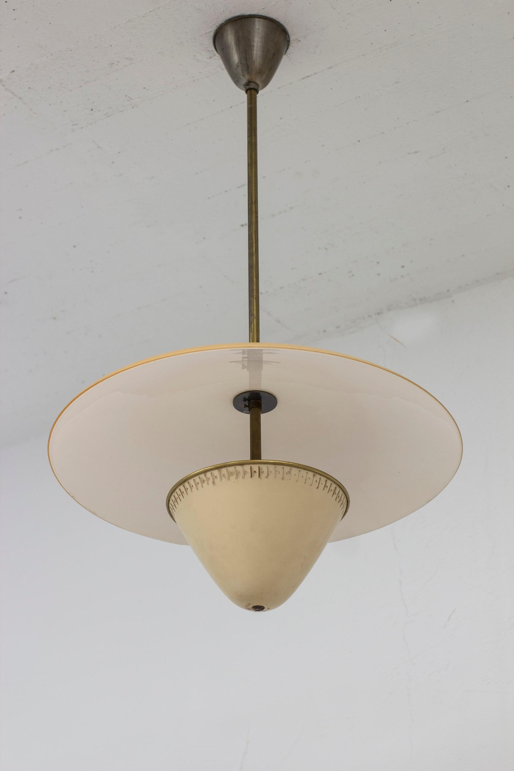 Ceiling lamp produced by ASEA belysning during the 1930s. Brass, ivory colored paint and amber colored glass diffuser. Ceiling canopy in aluminum. Good vintage condition with age related wear and patina. Very minor chip on the edge of the glass