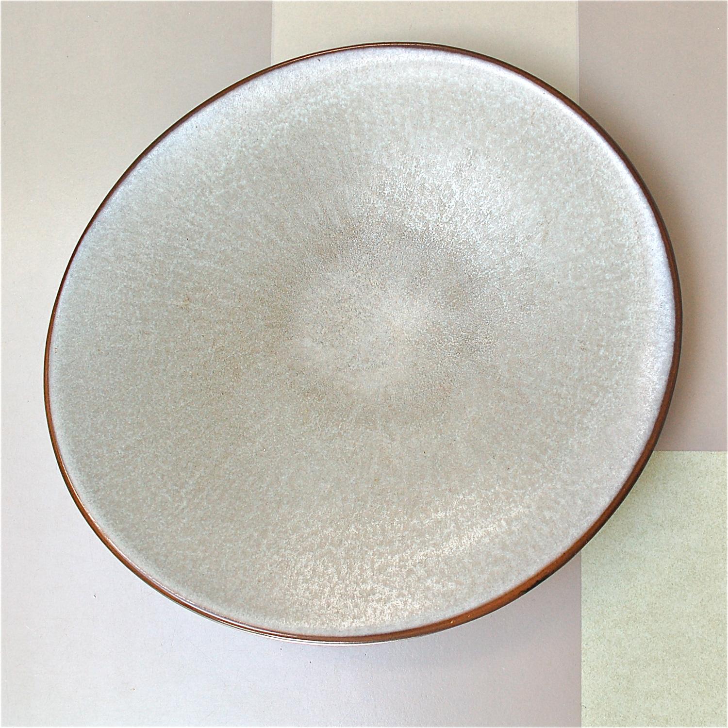 Modernist ceramic fruit bowl or dish in a distinctive asymmetrical curved design. The bowl has a light silvery and dark grey mottled finish at the top and a contrasting dark brown glaze underside. Made in the mid-20th century by German manufacturer