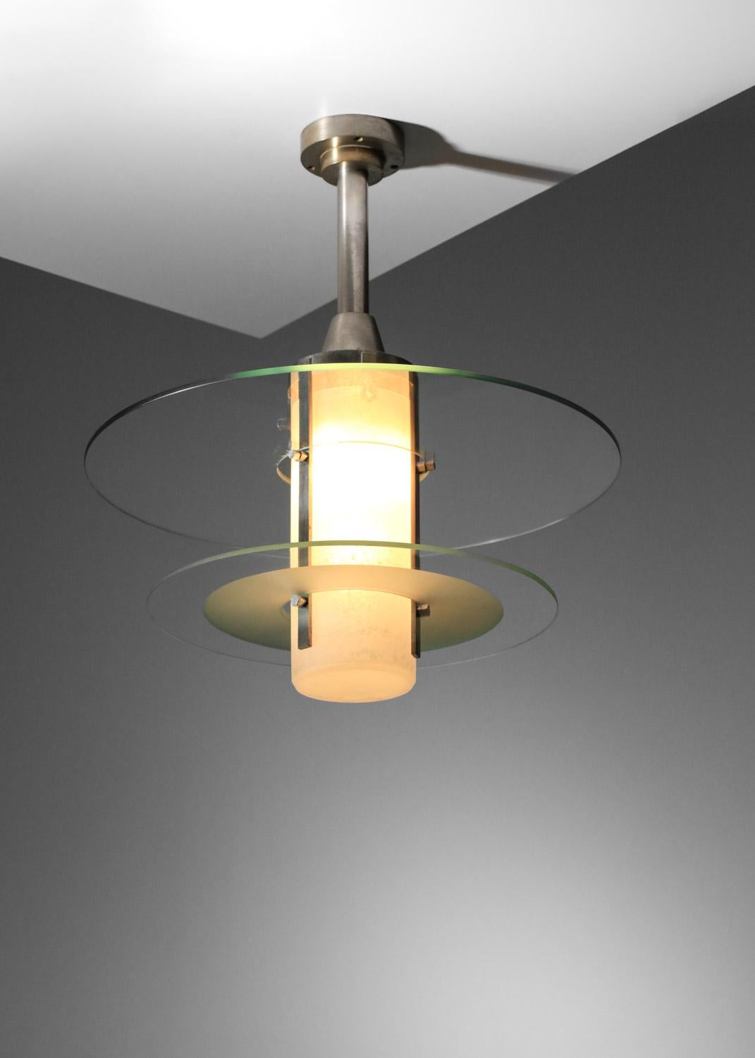 Suspension moderniste française des années 30/40. Structure en métal nickelé, diffuseur central en pâte de verre mouchetée. La suspension est agrémentée de deux disques en verre transparent. Design/One original et avant-gardiste pour l'époque. Très