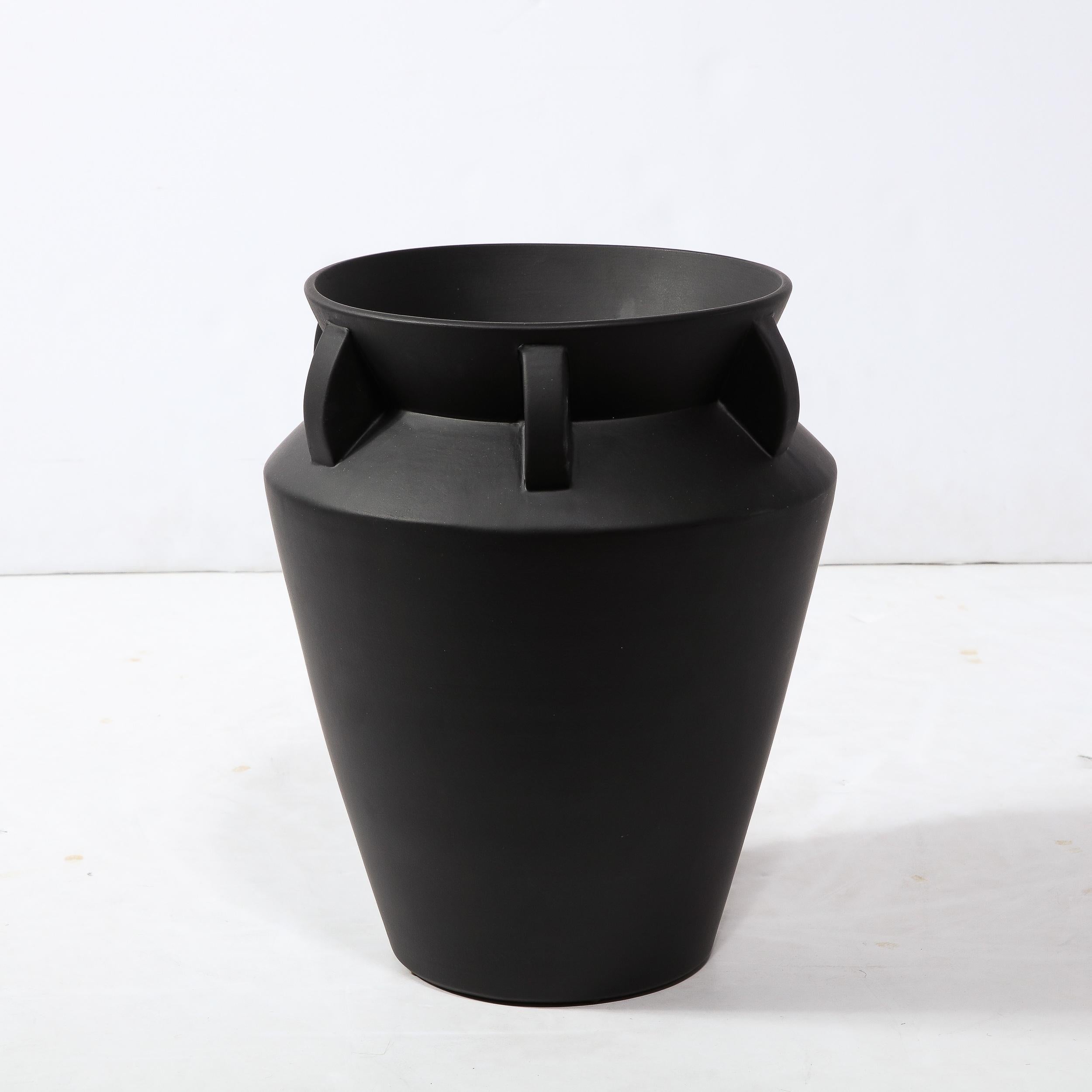 This elegant modernist urn form vase was realized in the United States during the latter half of the 20th century. It features a conical body that flares to an angled collar where it recedes meeting the neck that once again flares to a circular