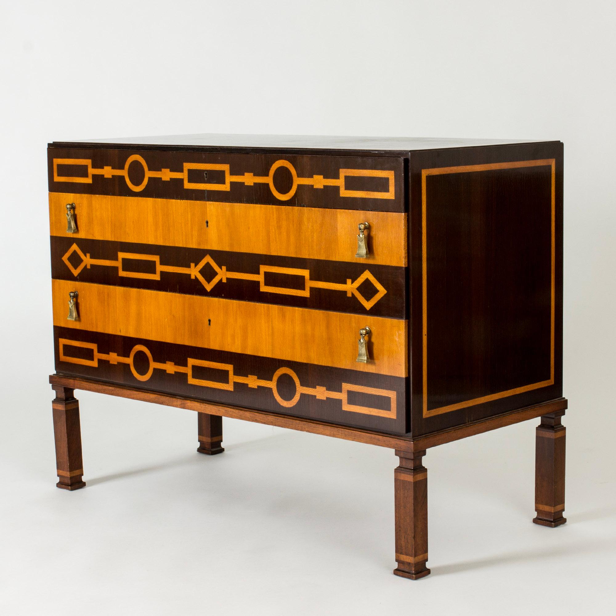 Stunning chest of drawers by Axel Einar Hjorth, made from birch with contrasting darker wood inlays. Geometrical pattern and beautifully sculpted legs in Swedish Grace style. Drawers handles in the form of brass tassels.

The model is called