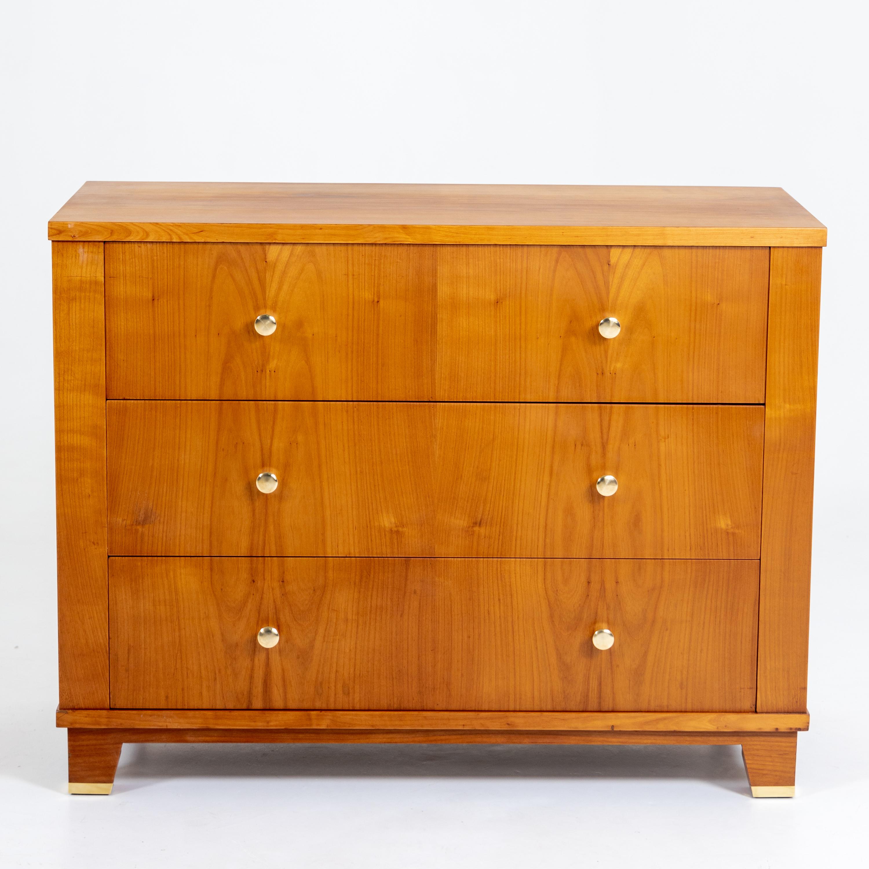 Dresser with three drawers and polished brass knobs made of cherry.