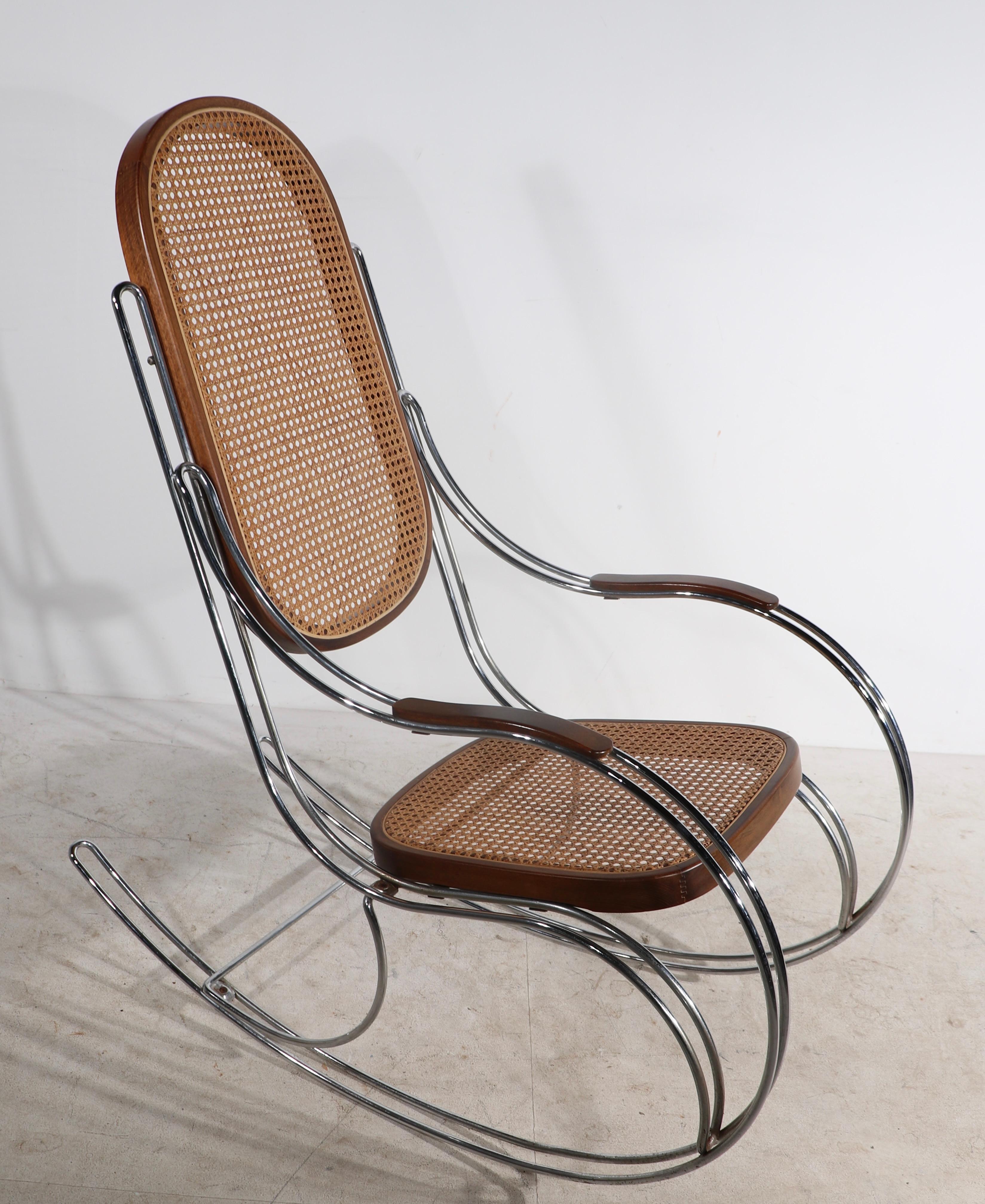 High style post modern design rocking chair having a chrome frame, with caned seat and back rest, with solid wood armrests. Design reminiscent of Milo Baughman, and Max Suaze, probably made in Italy, unsigned.