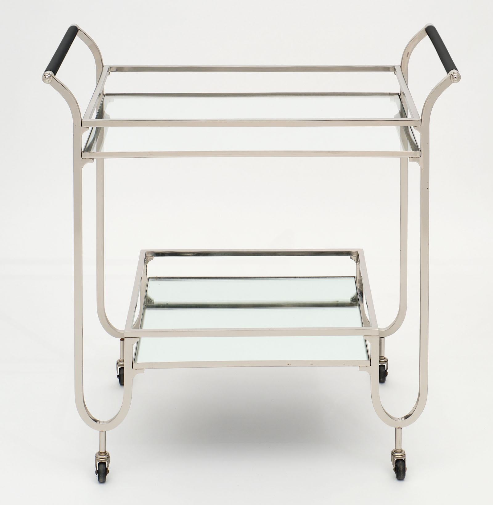Chrome and ebonized wood bar cart with two tiers. The bottom tier is mirrored, while the top shelf is clear glass. We love the clean lines and proportions of this piece. It is supported by wheels.