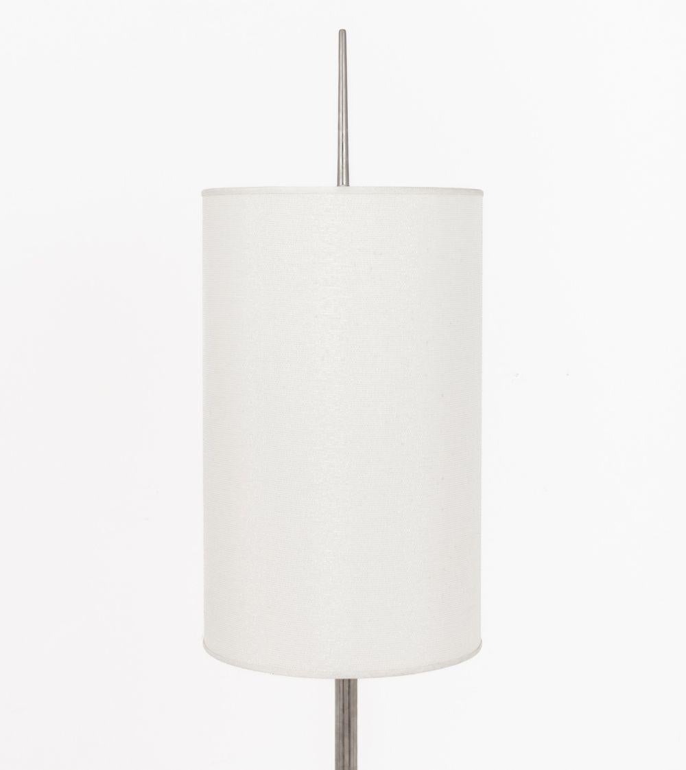 Lámpara de pie modernista de metal cromado, vástago de forma torneada con diseño geométrico sobre cuatro pies, con pantalla de lino. 75