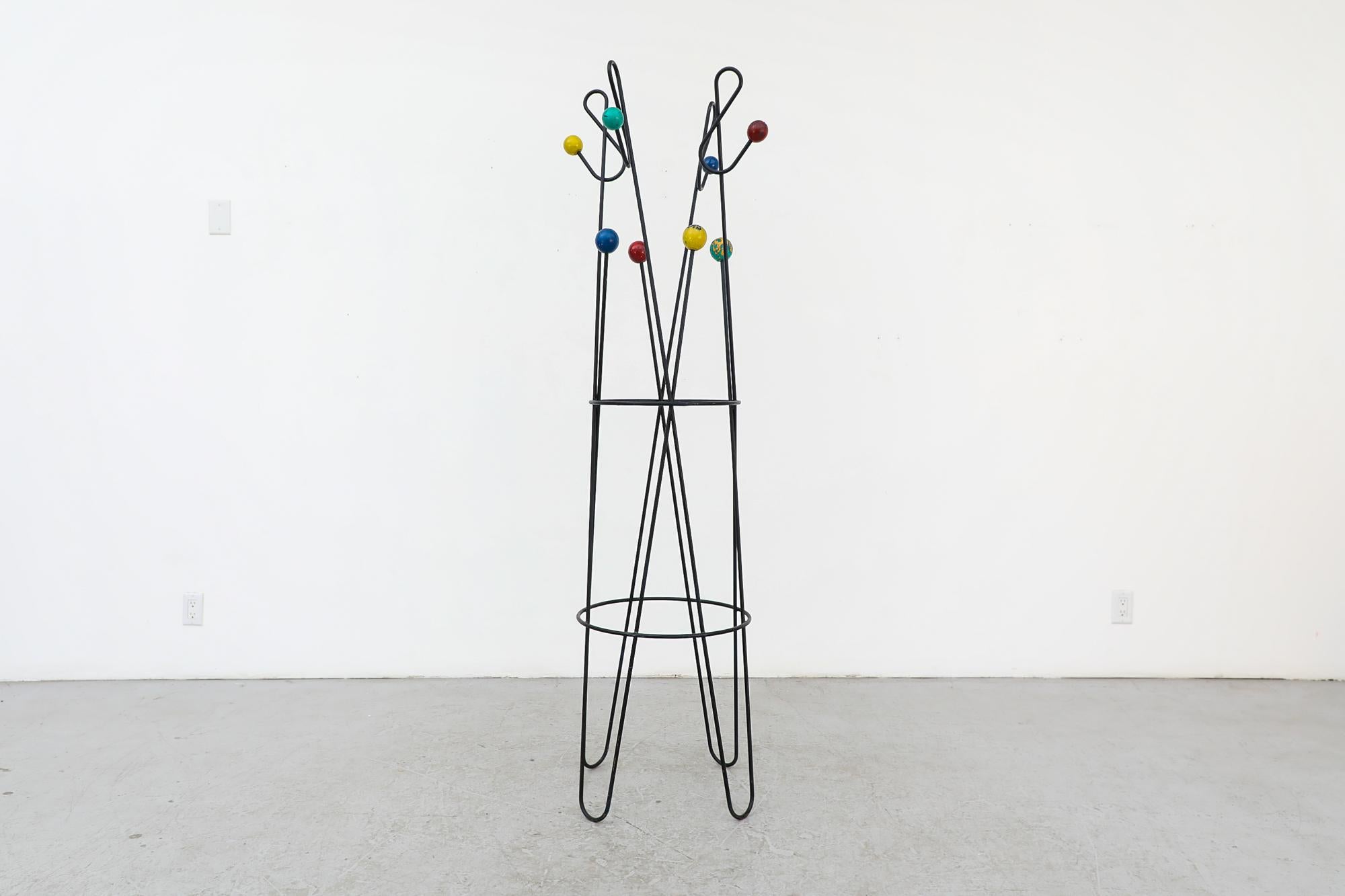 This modernist multi-color coat rack was designed in France by Roger Feraud. It features a freestanding iron frame and 8 lacquered wooden balls (2x red, 2x blue, 2x yellow, 2x green) with four treble clef shaped coat hooks at the top. In French 