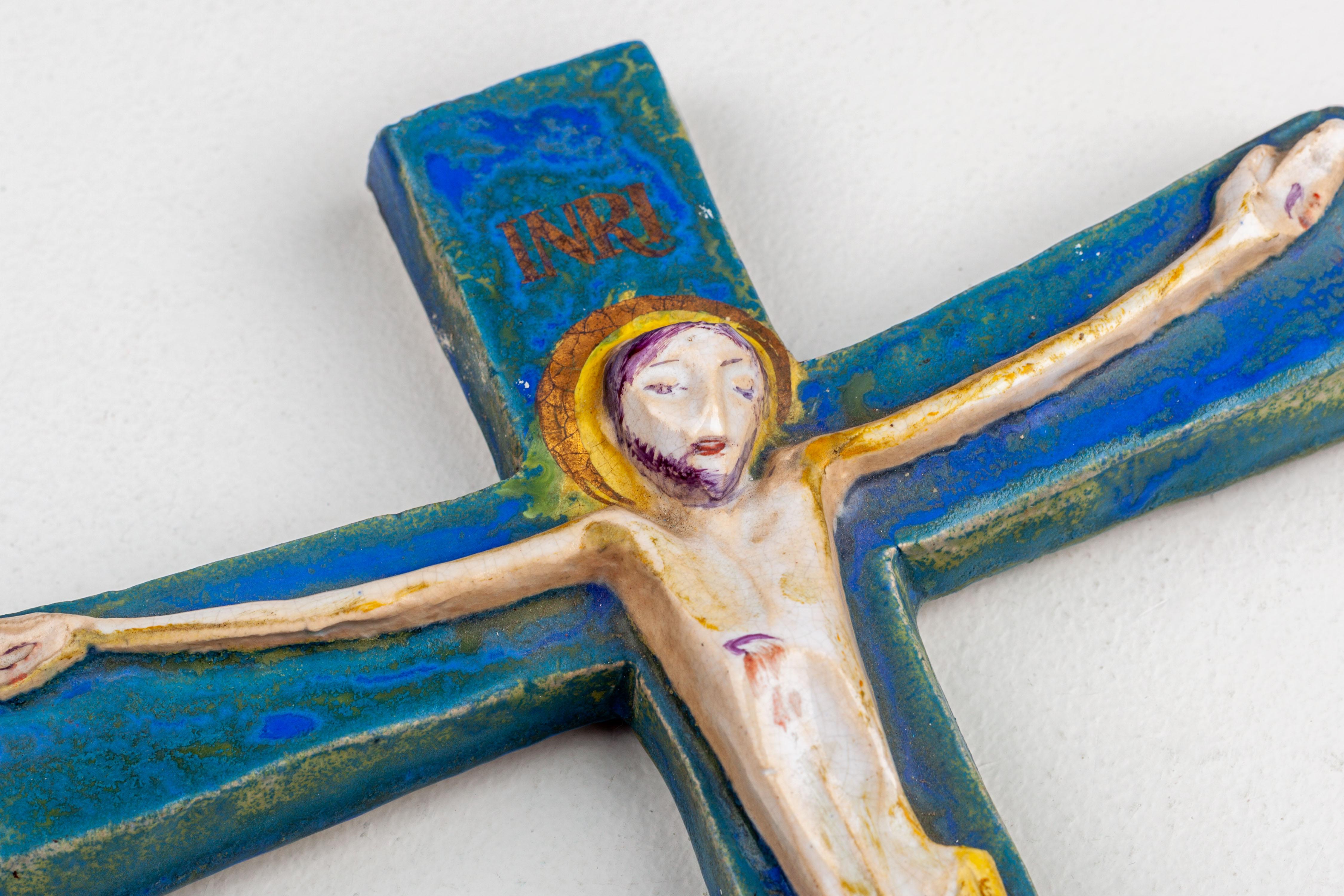 This modernist Studio Pottery wall cross, meticulously crafted by a European artist, features a cobalt blue crucifix enriched with subtle gold accents cross, bearing an exceptional modernist interpretation of Jesus Christ with a tranquil