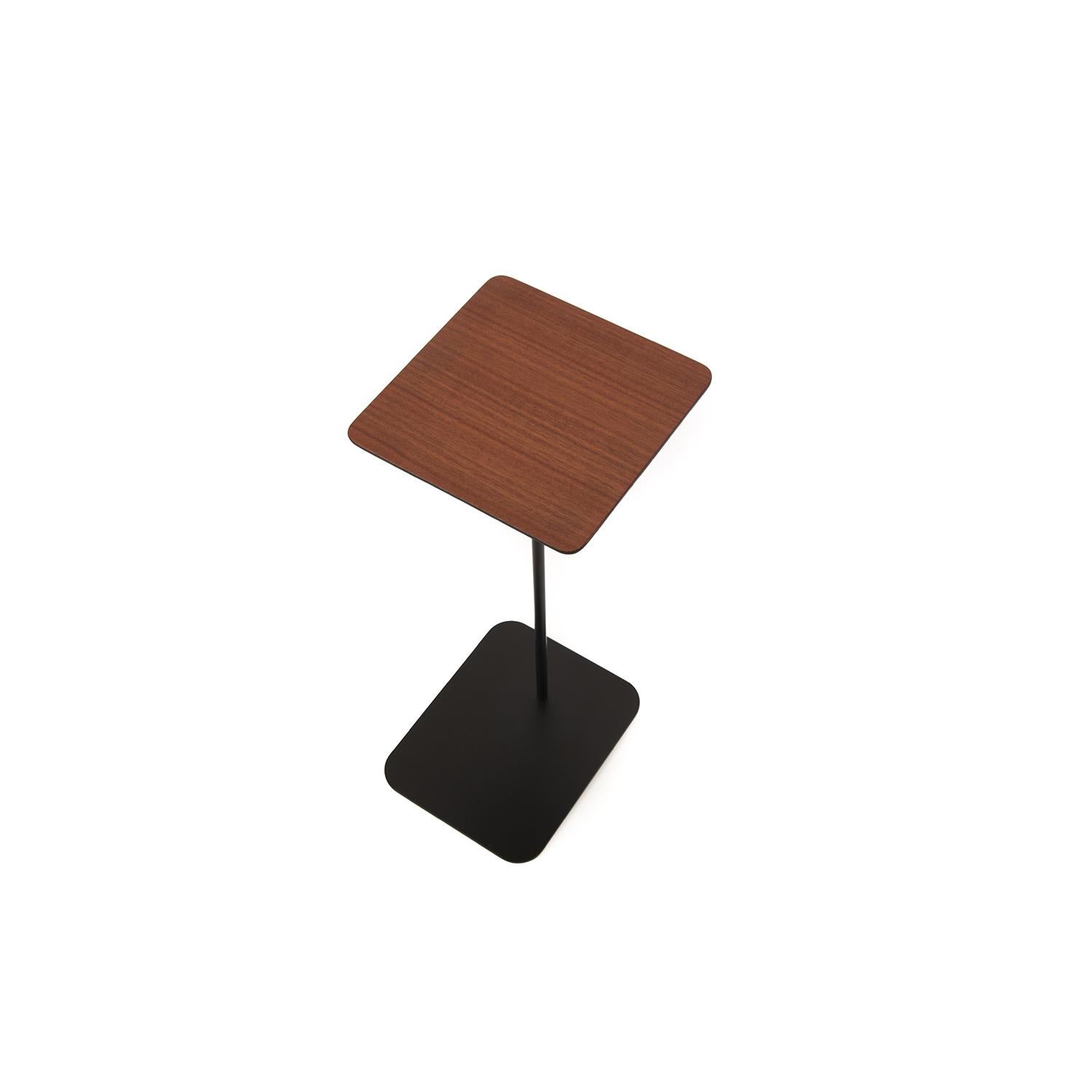 This square top makore wood table sits upon a slender, black stem with rectangular a base.