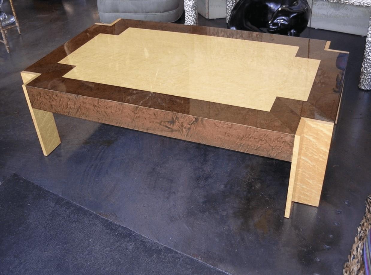 A two-tone birds eye maple coffee table with clipped corners. Finish is in a beige and medium-brown lacquer.