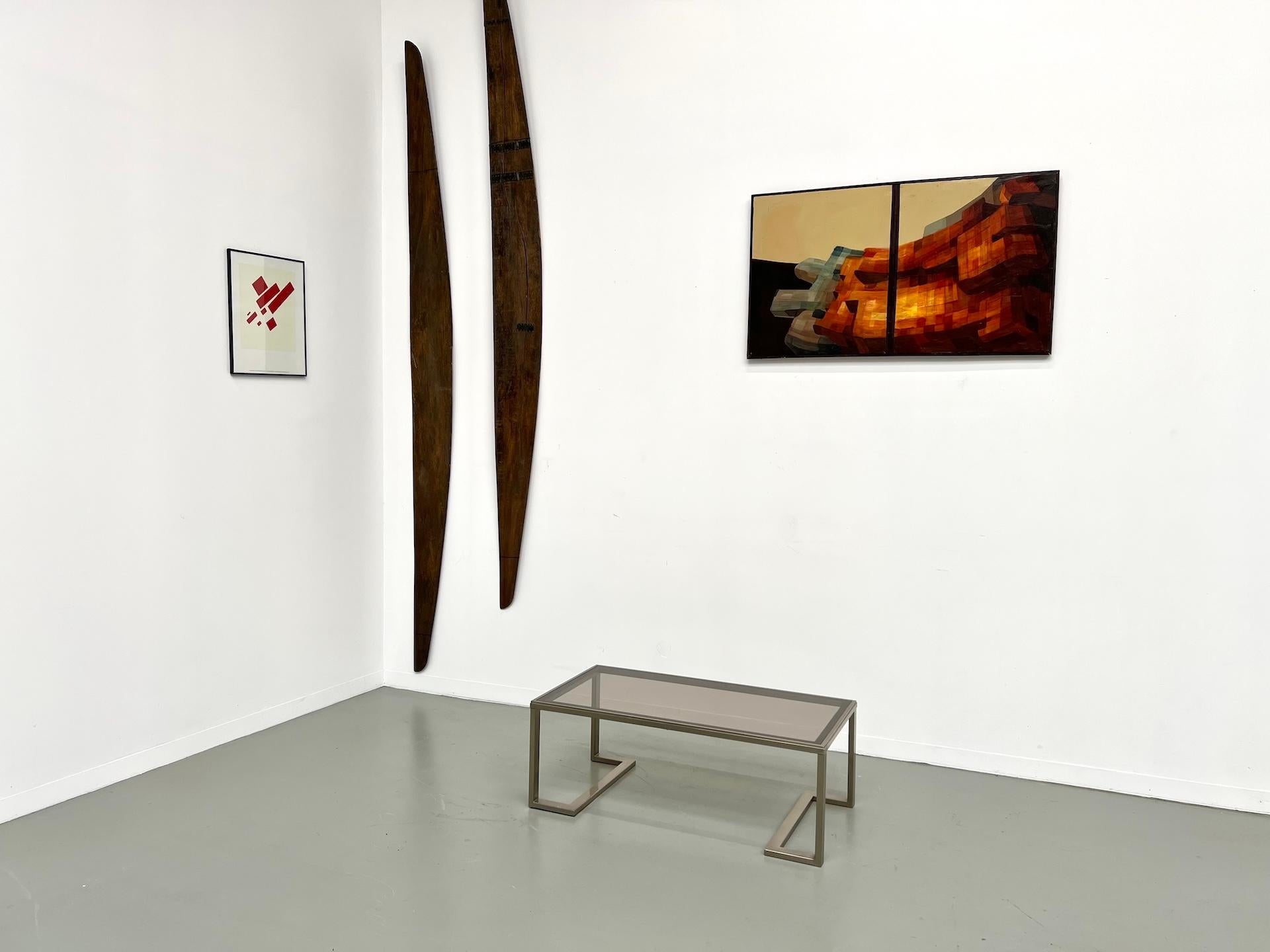 Maison Lecan presenta esta mesa de centro modernista de los años 70, fabricada en metal y cristal.

La tapa rectangular de cristal ahumado descansa sobre una estructura de latón cepillado (tono champán), con patas en forma de U invertida unidas en