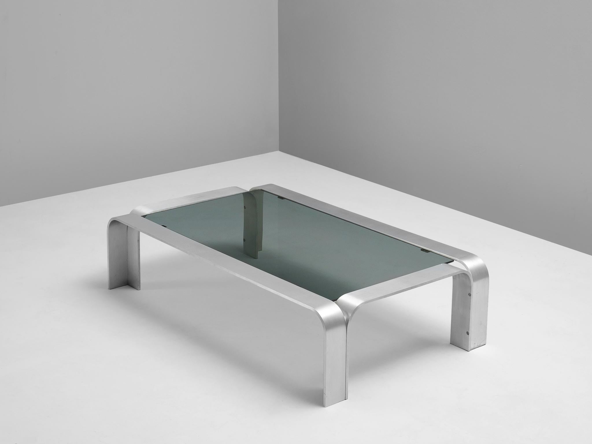 Coffee table, aluminum and glass, European, 1970s.

Modernist coffee table. The rectangular table is accompanied by a dark glass top. The aluminum frame consist of four bended arches. The frame is manufactured from metal strips and rounded edges.