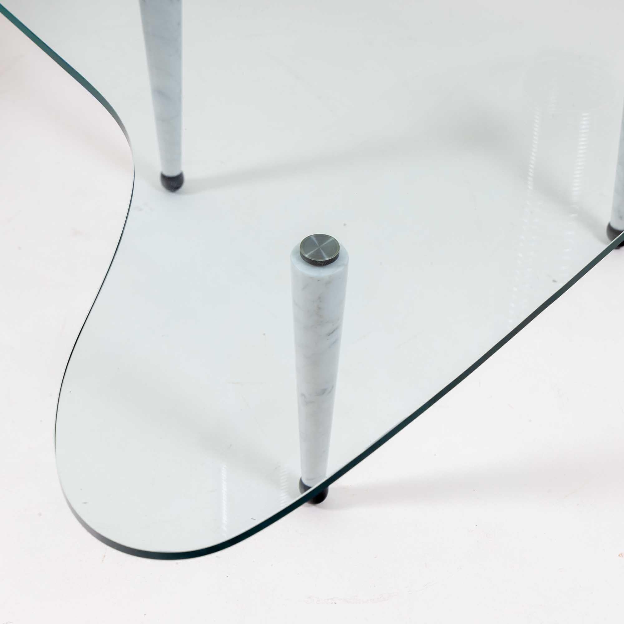Table basse italienne sculpturale avec plateau en verre en forme de boomerang. 
La table repose sur trois pieds coniques en marbre blanc.