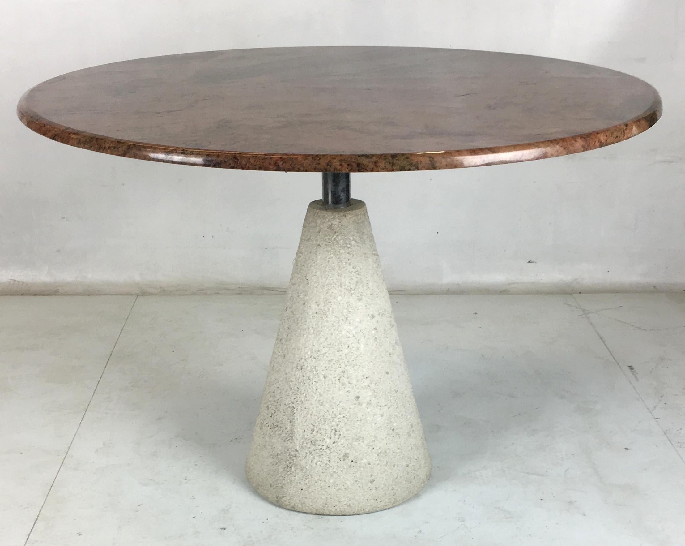 Modernist dining table consisting of a rough concrete inverted cone base with a polished stainless steel neck supporting a beautifully figured granite top. This table is a stunning modern statement piece.