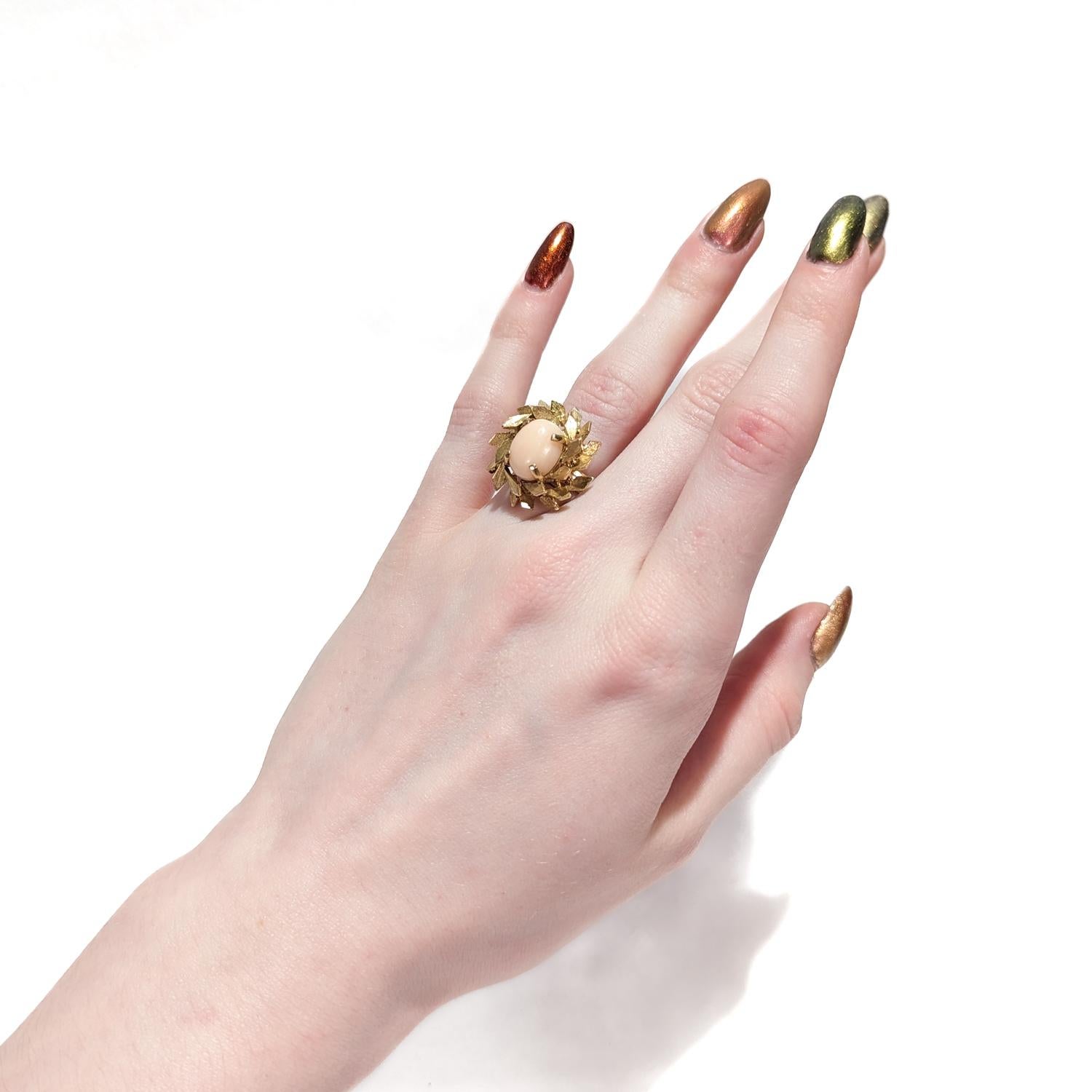 A very fine coral and 14k gold floral ring.

With a pink or peach colored oval coral cabochon prong center set and surrounded by 14 karat gold leaf patterns.

Date:
20th Century

Overall Condition:
It is in overall good, as-pictured, used estate