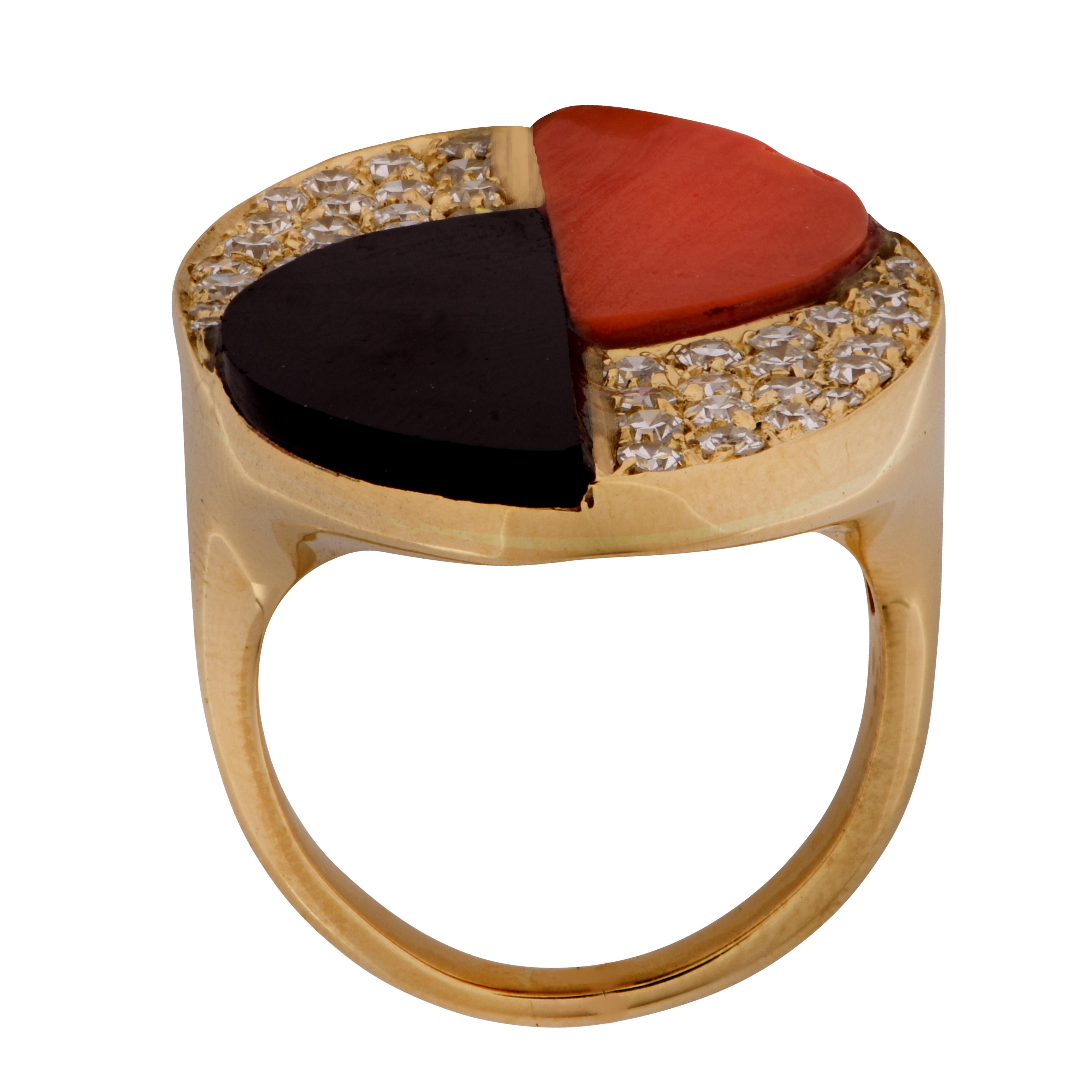 Sensational Modernist ring crafted in 18 karat yellow gold, featuring coral and onyx semi-circular discs accented by 40 single cut diamonds weighing approximately 1 carat, G color, VS clarity, set in an oval design. The face of the ring measures