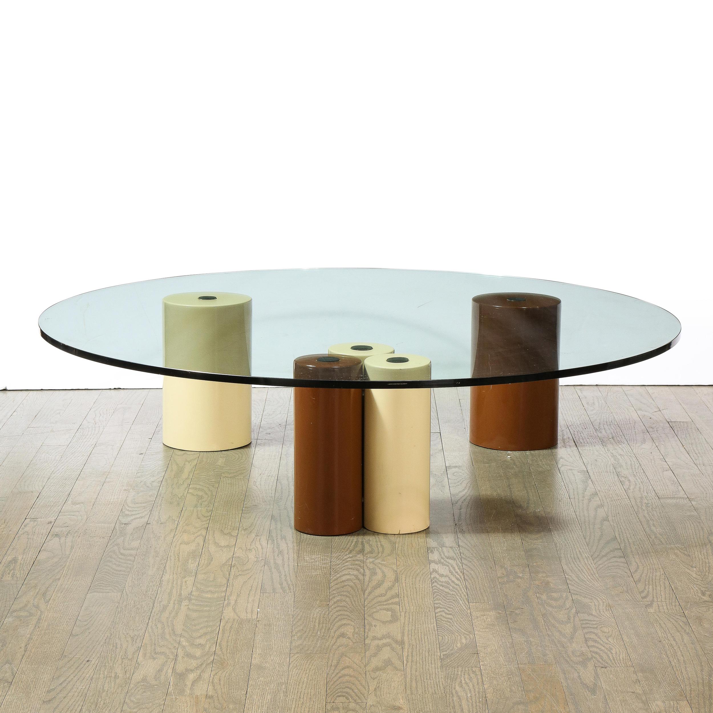 This refined and sophisticated modernist cocktail table was realized by the esteemed maker Saporiti in Italy, circa 1980. It features five cylindrical pillars- three in cream and two in ochre- that support a circular glass top. With its
