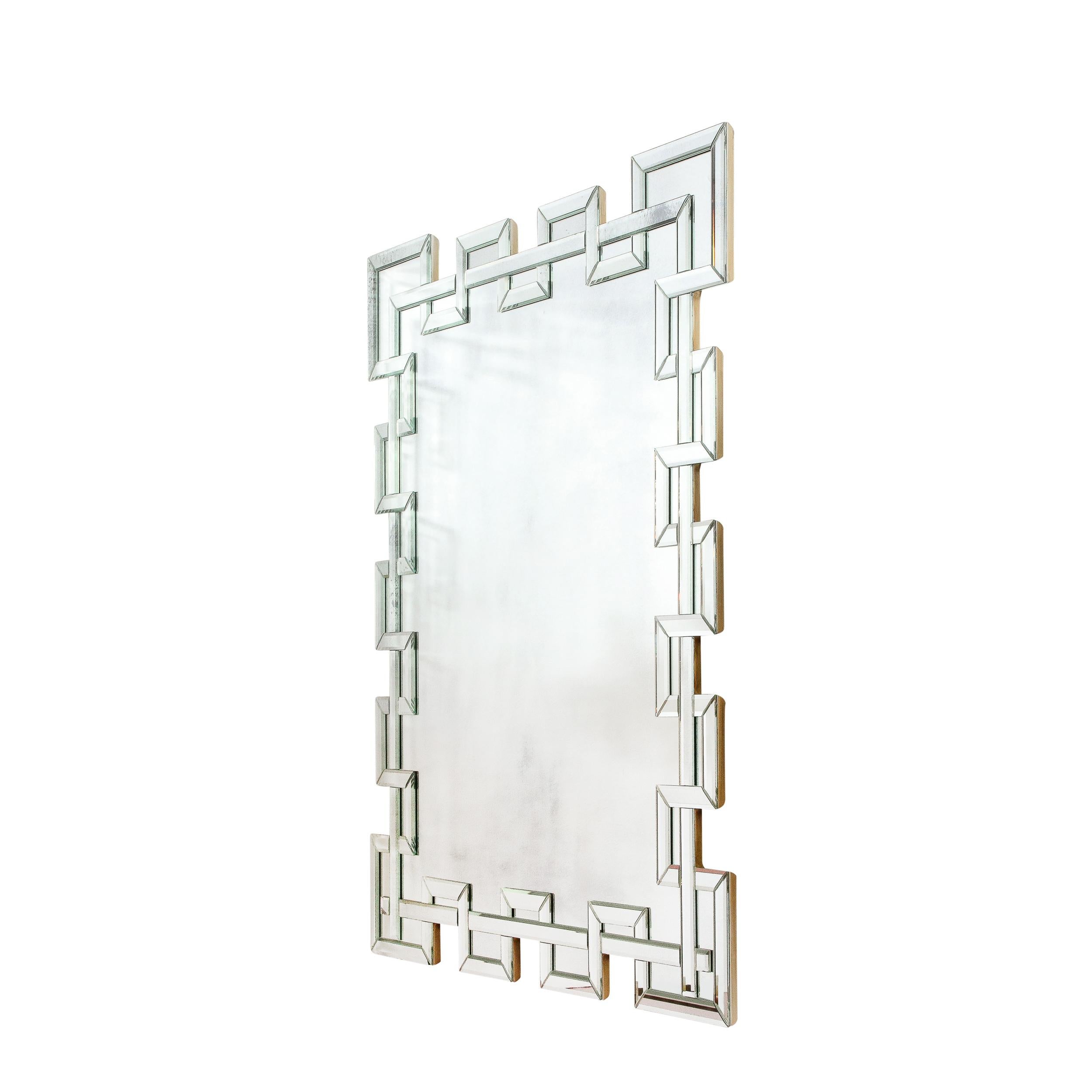 This stunning and graphic crenellated modernist mirror was realized in the United States during the late 20th century. It features a rectangular form with an interlaced geometric border in which beveled linear segments of mirror weave in and out of