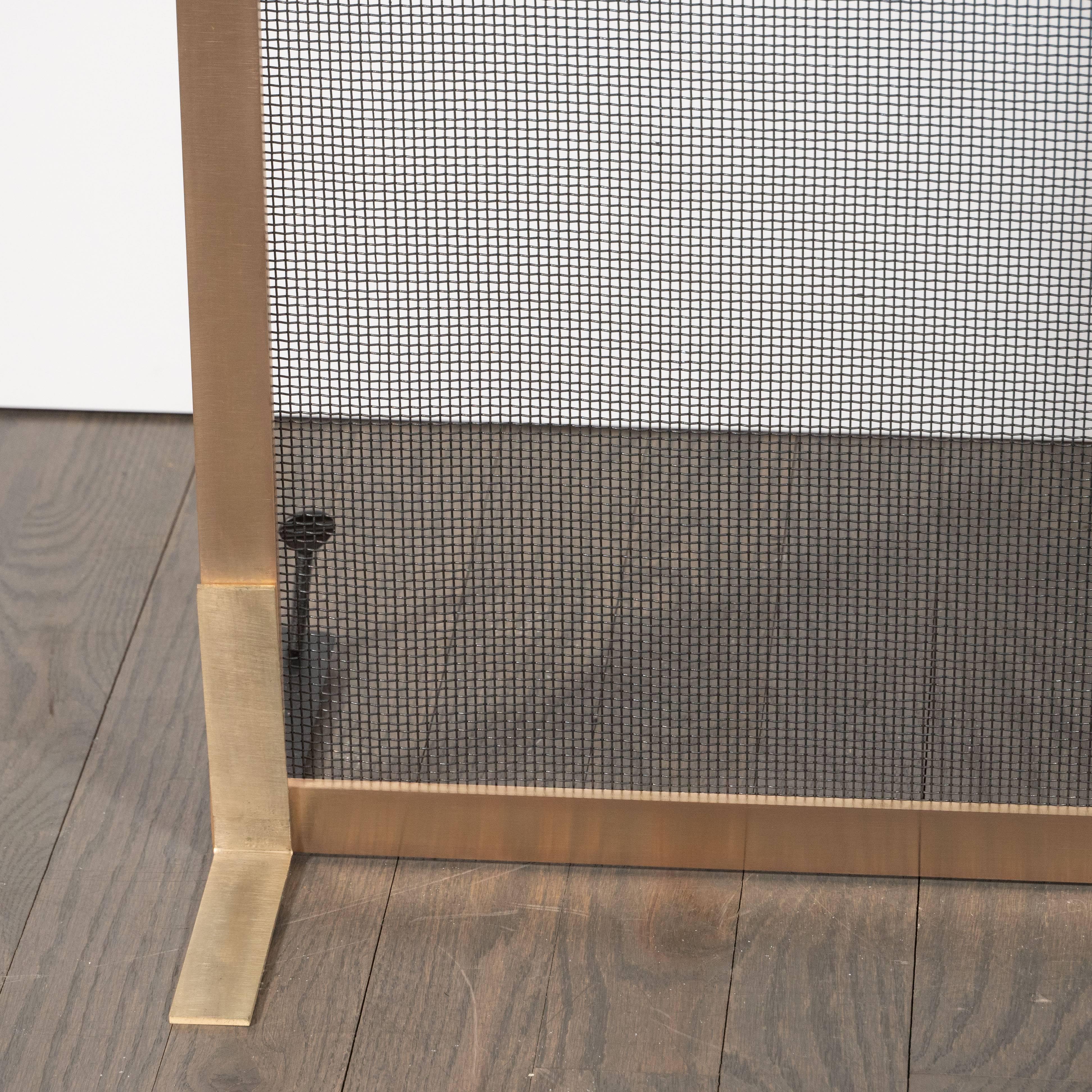 This stunning modernist fire screen was custom made by artisans in New York State. It features an austere square body in brushed brass, with rectangular feet in the same material and a black iron mesh grill executed in a rectilinear weave. With its