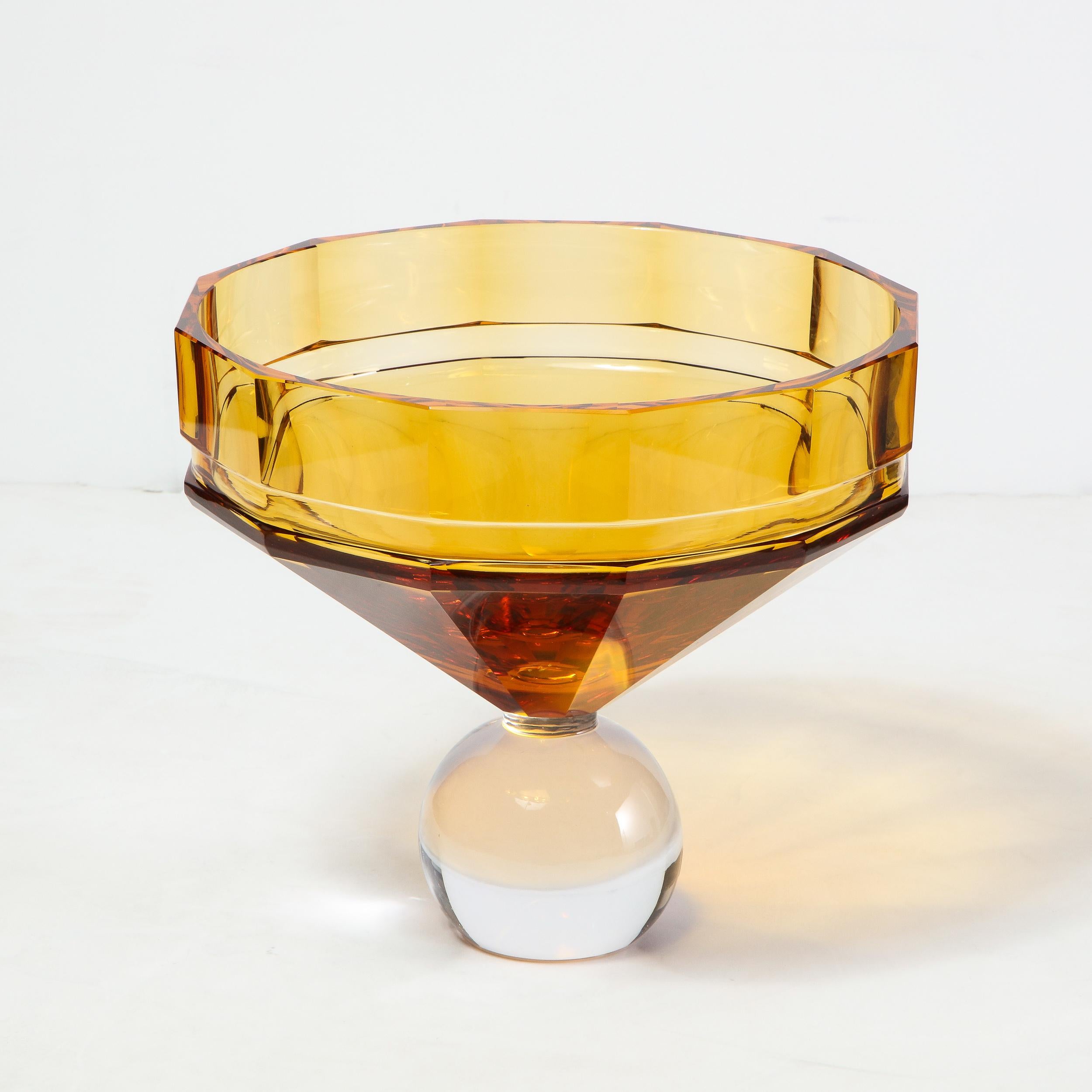 This stunning modernist glass center bowl was realized in the Czech Republic by the legendary maker Moser. It features a spherical translucent foot; an angled amber neck and faceted top that beautifully refracts light. With its sophisticated palate