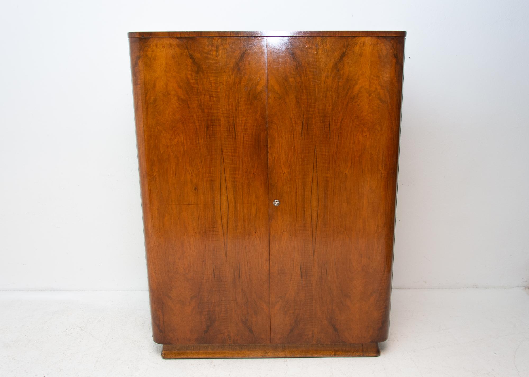 Vintage Czechoslovak modernist wardrobe, made in Czechoslovakia in the 1950s. It is made of walnut wood and plywood. This item is in very good vintage condition, with only slight signs of age and using, a small chip of veneer on the back of the