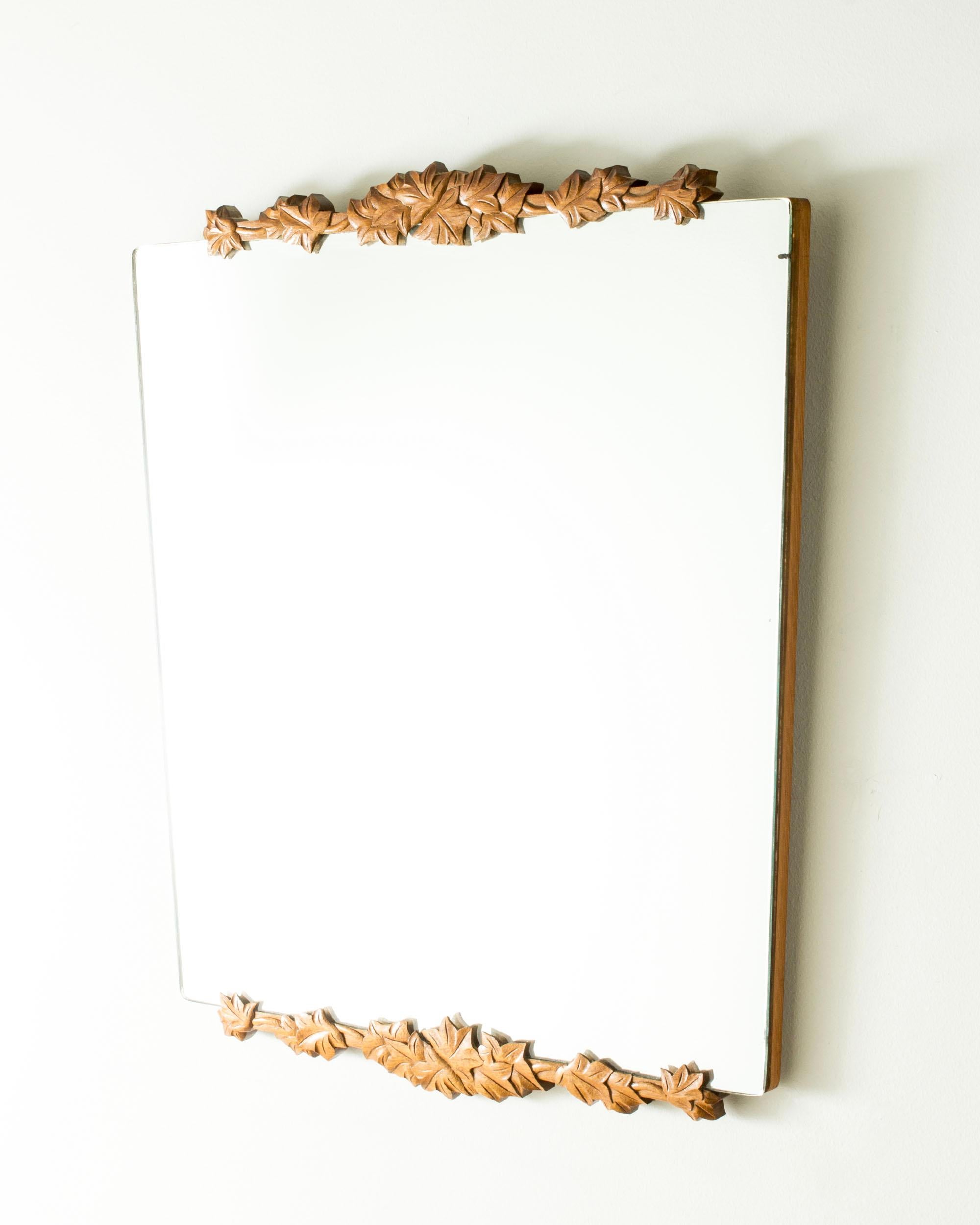 Schöner schwedischer moderner Wandspiegel in breiter, spitz zulaufender Form. Dekor aus klobigen Holzblättern oben und unten, sehr schöne Liebe zum Detail.