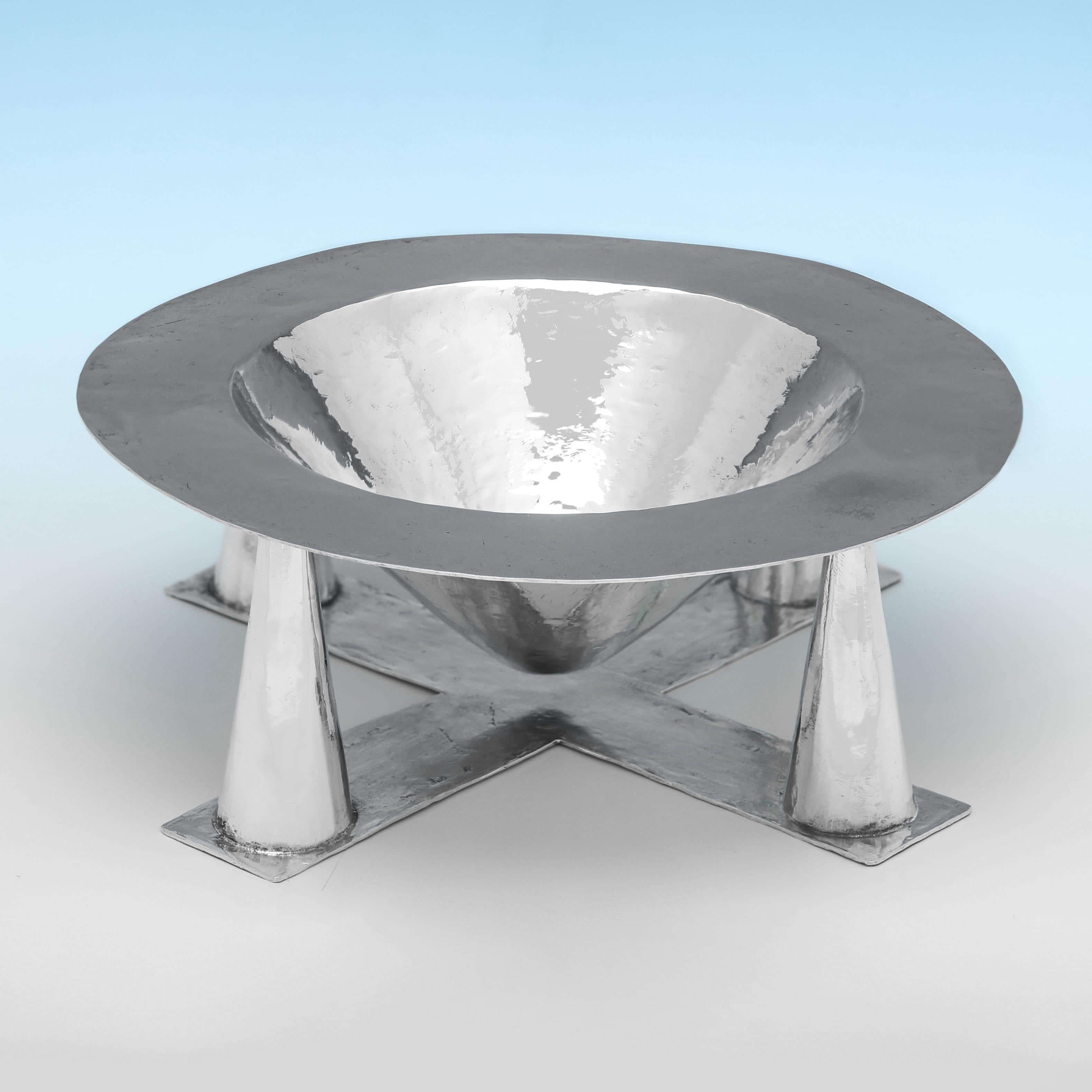 Hallmarked in London in 1992, this sterling silver bowl is the work of British artist-silversmith Bryan Laurence Illsley, known for his sculptural approach to functional forms. The piece is circular with a broad, flattened rim and a hammered finish,