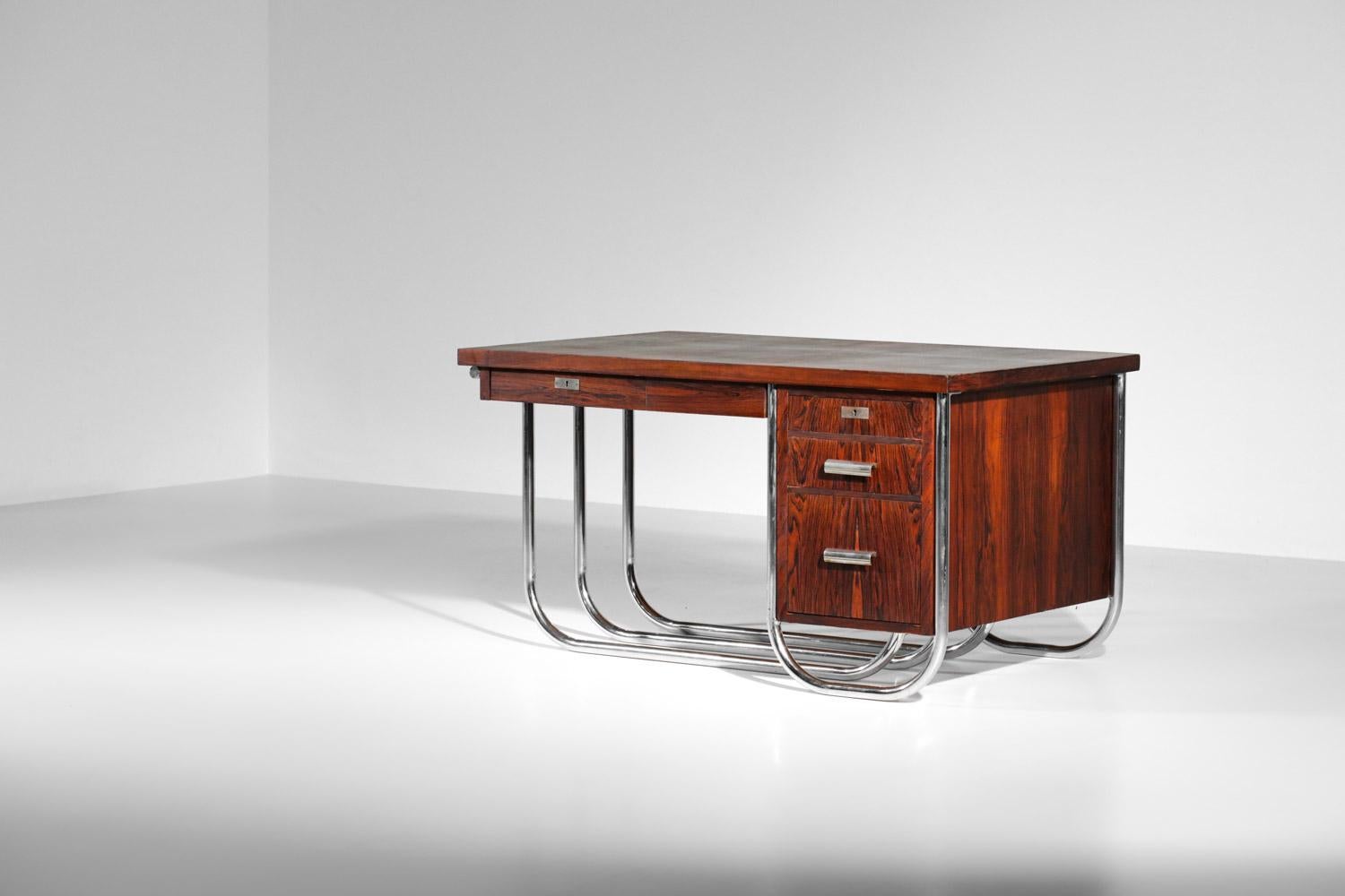 Bureau français des années 40/50 dans le style moderniste Bauhaus. Structure du bureau en palissandre de Rio plaqué et massif avec un triple piétement tubulaire en acier chromé assez rare. Le bureau est composé d'un caisson à trois tiroirs et d'un