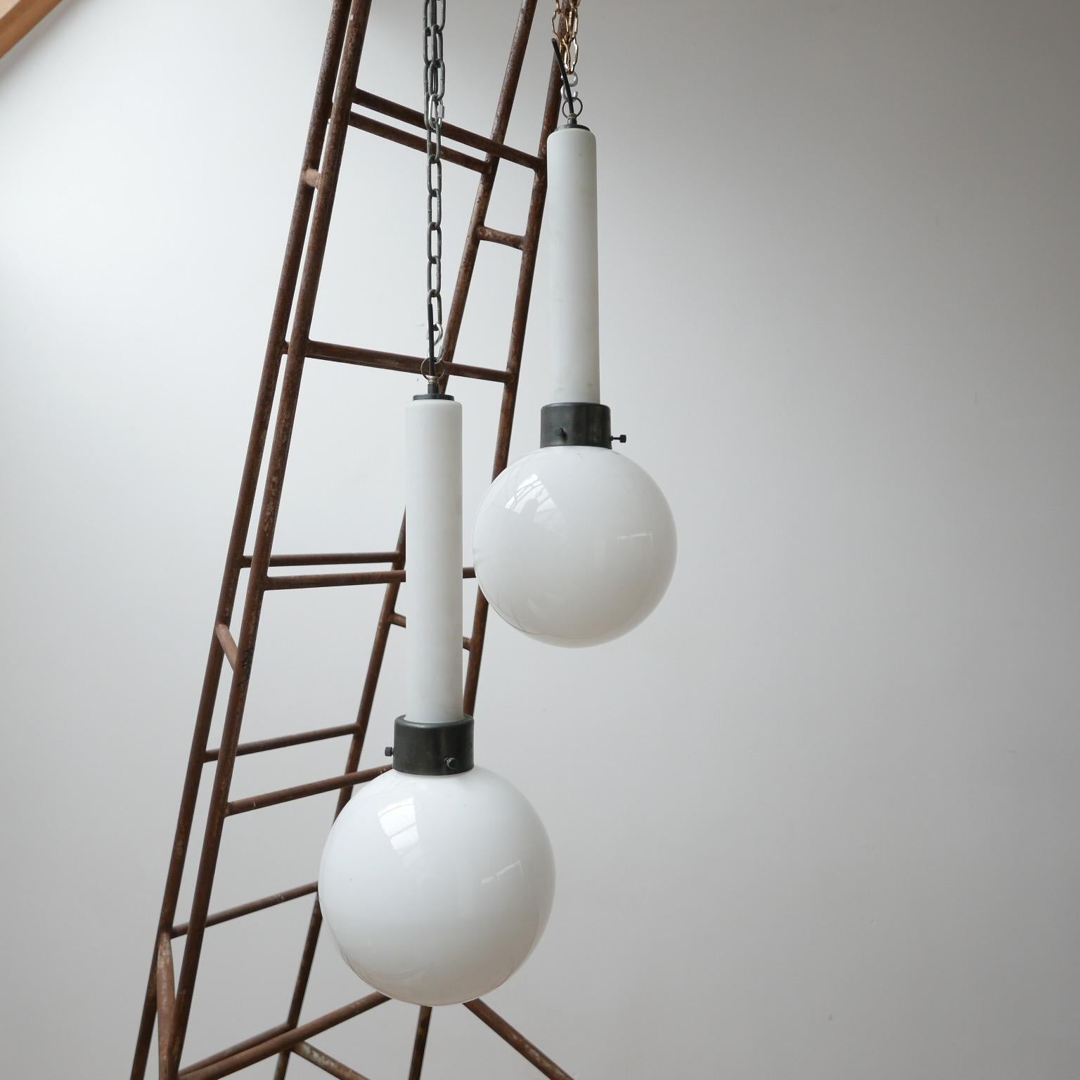 Highly unusual glass opalone pendant lights. 

The pendants are made from two parts of glass, a matte opaline long tube and an opaline globe where the bulb holder emits from. 

From a modernist church in Holland. 

Re-wired and PAT tested.