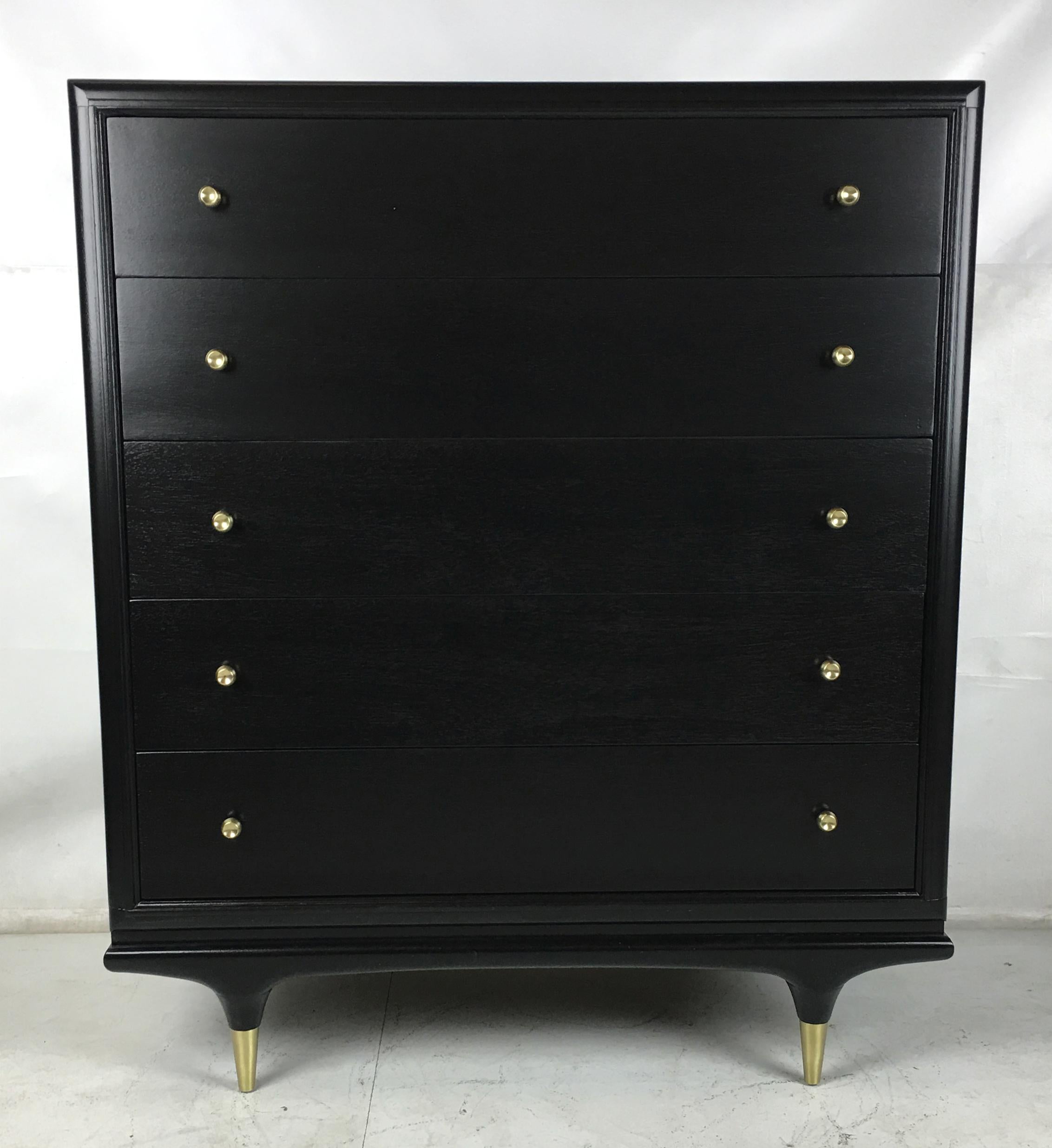 Ebonized Walnut highboy dresser with stiletto legs and solid brass drawer hardware. The legs have long tapered brass sabots. The dresser has been meticulously refinished in open grain black lacquer and the brass mounts have been freshly polished and