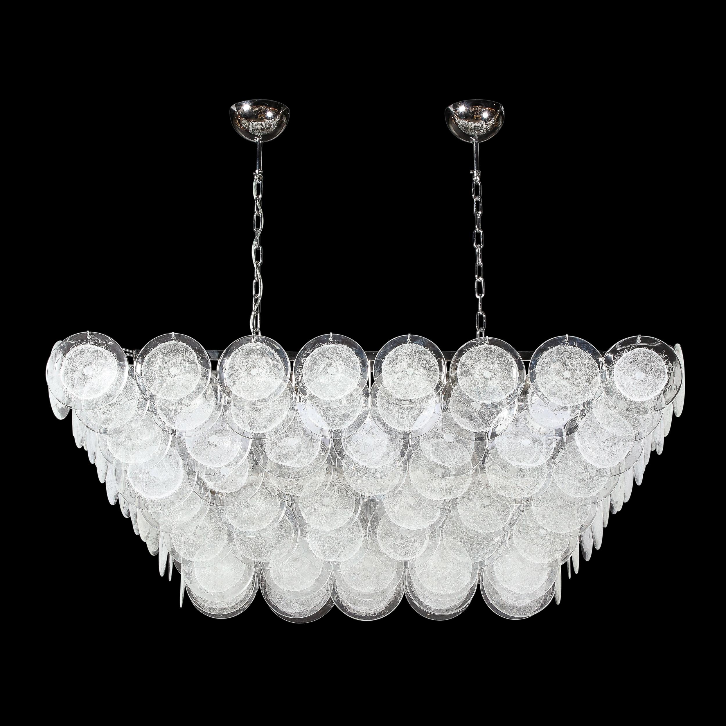 This stunning modernist elongated chandelier was handblown in Murano, Italy- the island off the coast of Venice renowned for centuries for its superlative glass production. It offers an inverse volumetric trapezoidal form from which an abundance of