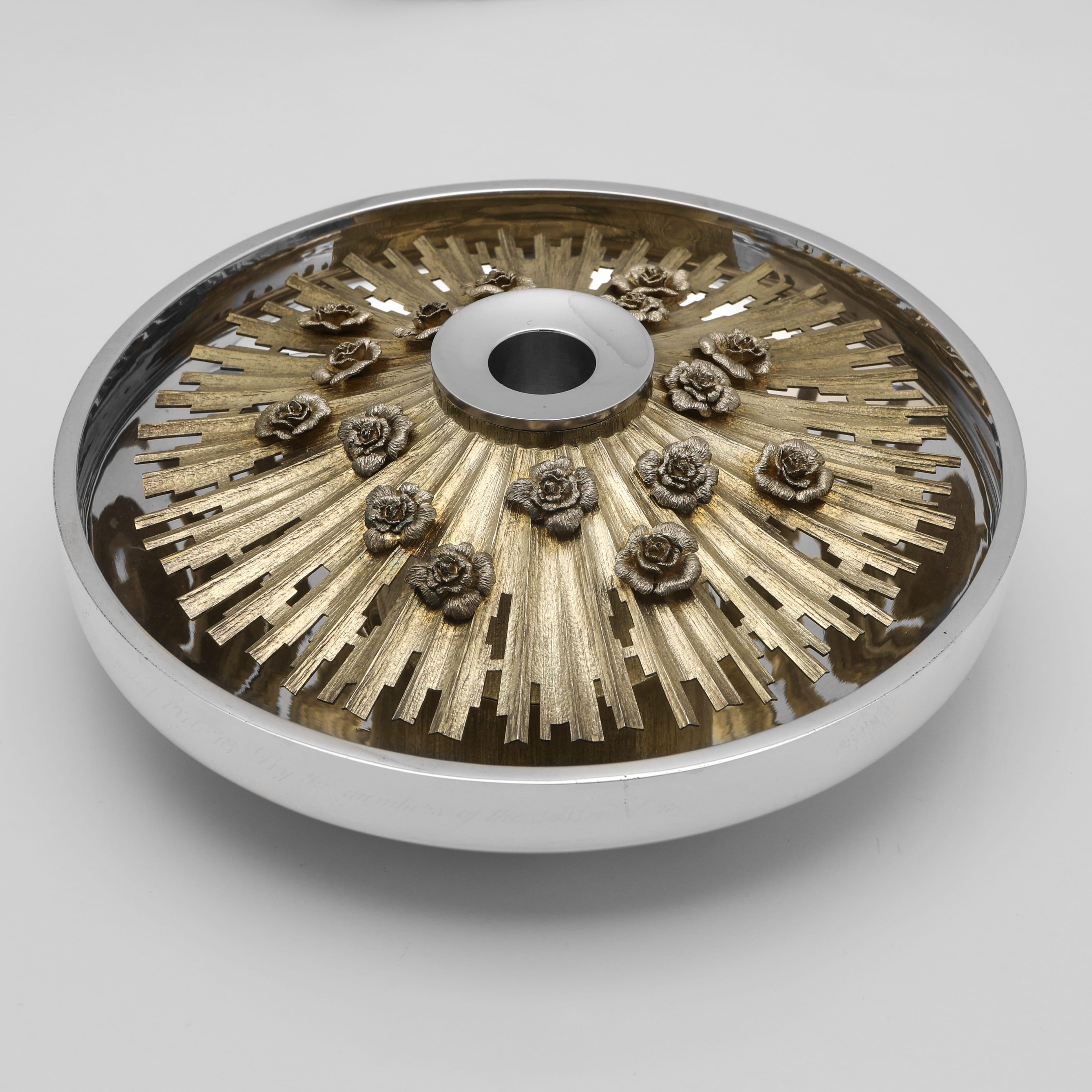 Hallmarked in London in 1978 by Christopher Lawrence this striking sterling silver centrepiece is of a low, circular form with a wide, polished rim. The piece features a removable gilt-metal insert decorated with a radiating 'sunburst' pattern and