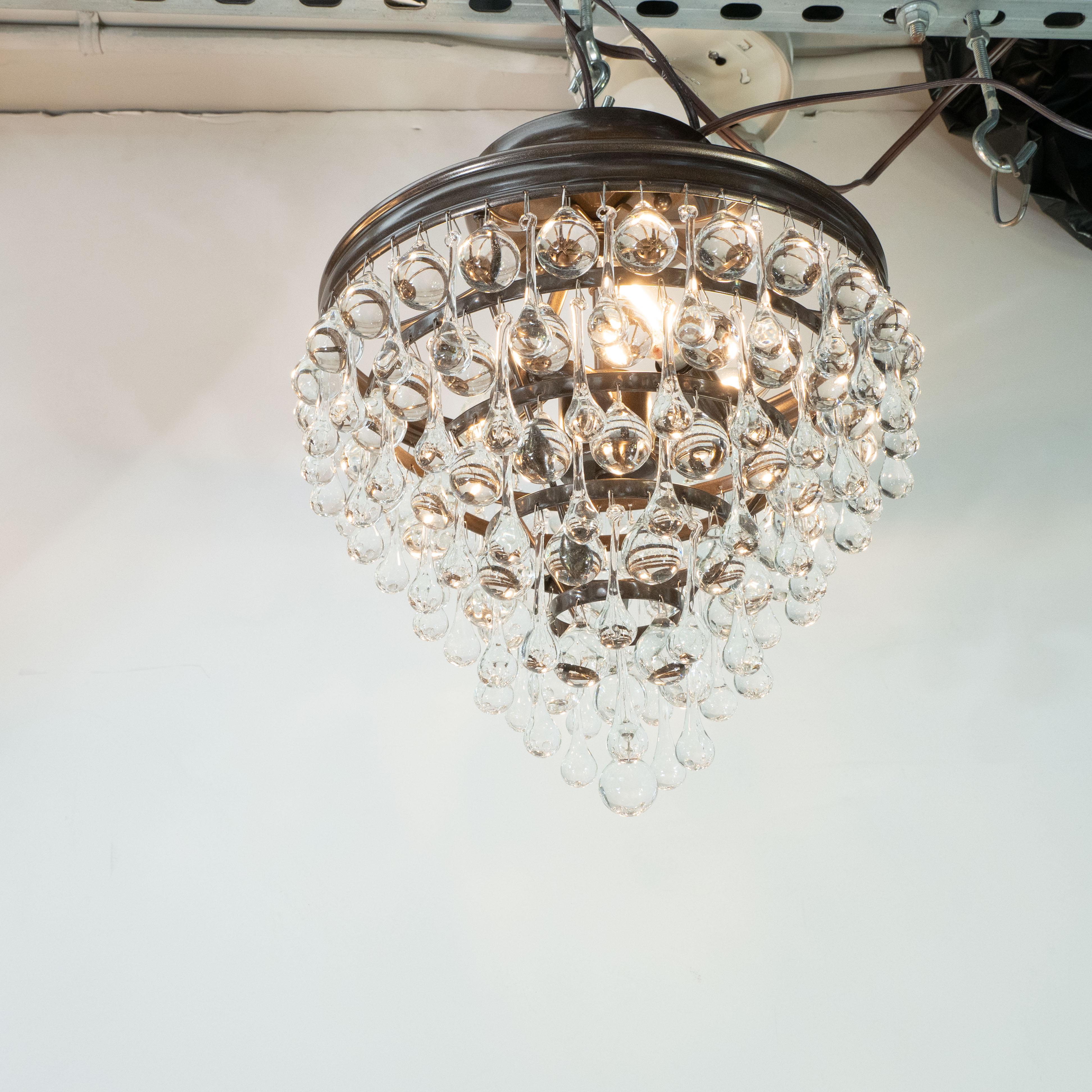 This stunning five-tier modernist chandelier was realized in the United States. The fixture offers an abundance of hand blown translucent tear drop forms hanging from an oil rubbed bronze body. At once sophisticated and whimsical, this piece