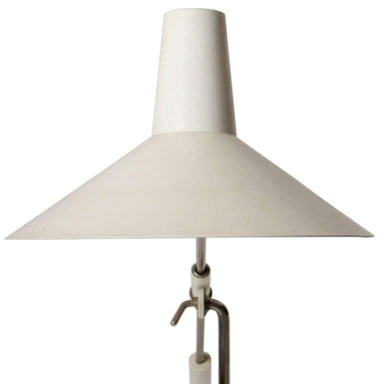 A modernist adjustable white lacquered and steel floor lamp having a locking counterweighted arm and pivoting hood attached to a nickeled steel stem rising from a marble disc base.
