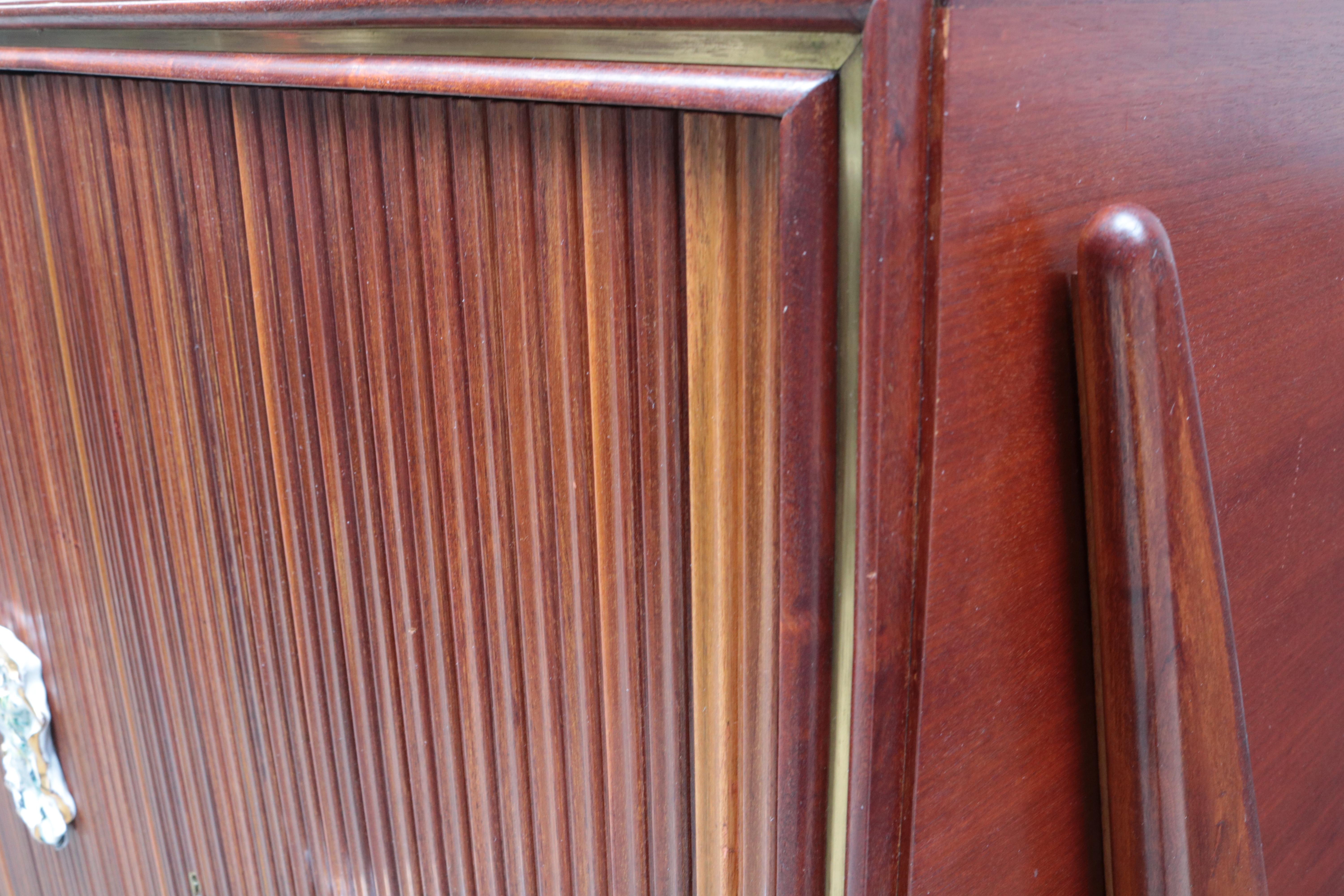 Armoire moderniste à quatre portes d'Oswaldo Borsani
avec des tirettes en céramique de Frederico Quatrini.
Acajou avec accents en laiton et poignées en céramique.
Chaque tirette en céramique est signée : Frederico Quatrini.
  